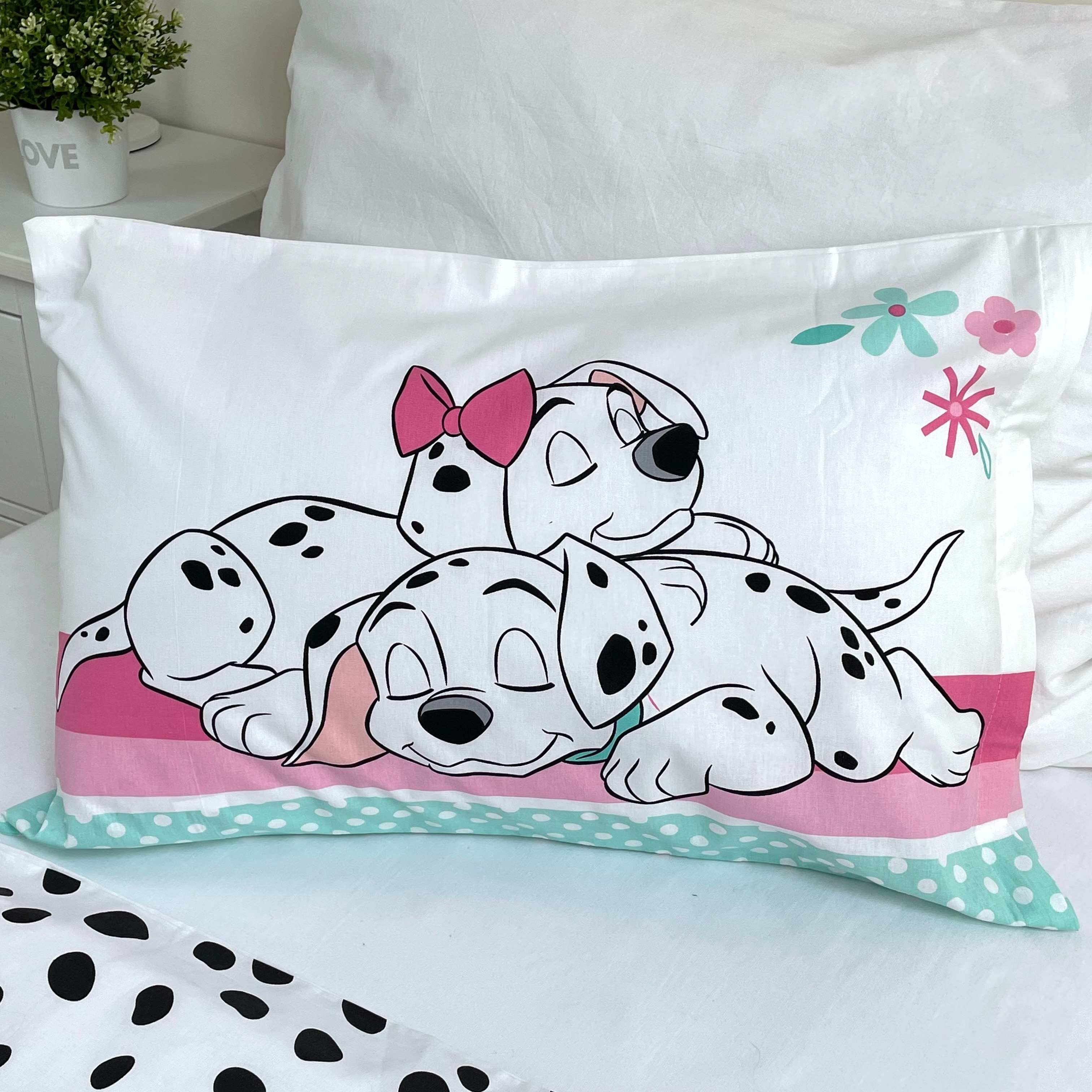 Kissenbezug mit Cartoon-Dalmatinerhunden. Der Hintergrund zeigt ein weißes Bett und eine Pflanze auf einem Nachttisch.
