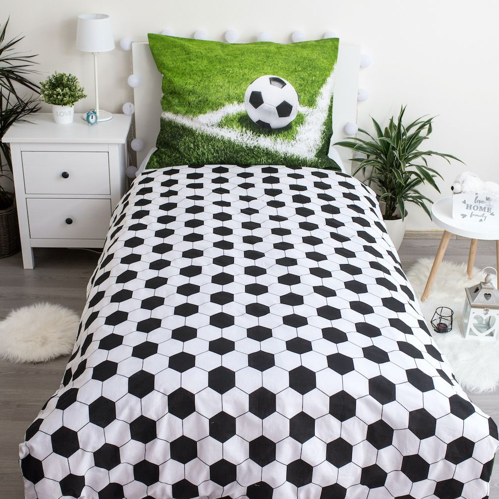 Ein Bett mit Fußball-Bettwäsche. Das Kissen zeigt einen Fußball auf Rasen. Die Bettwäsche hat ein schwarz-weißes Fußballmuster.