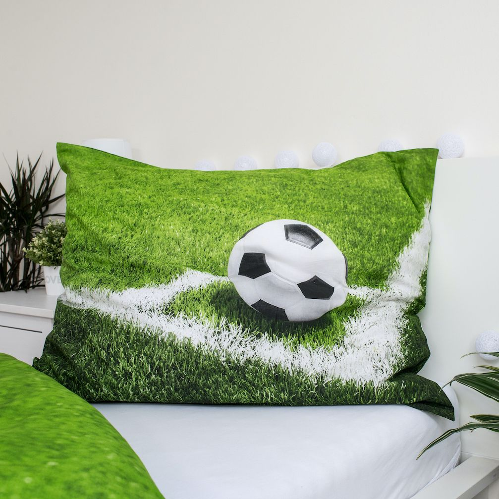 Kissen mit Fußballfeld-Design und Fußball. Weißes Bett und Wand. Pflanzen an der Seite. Dekorative weiße Lichter.