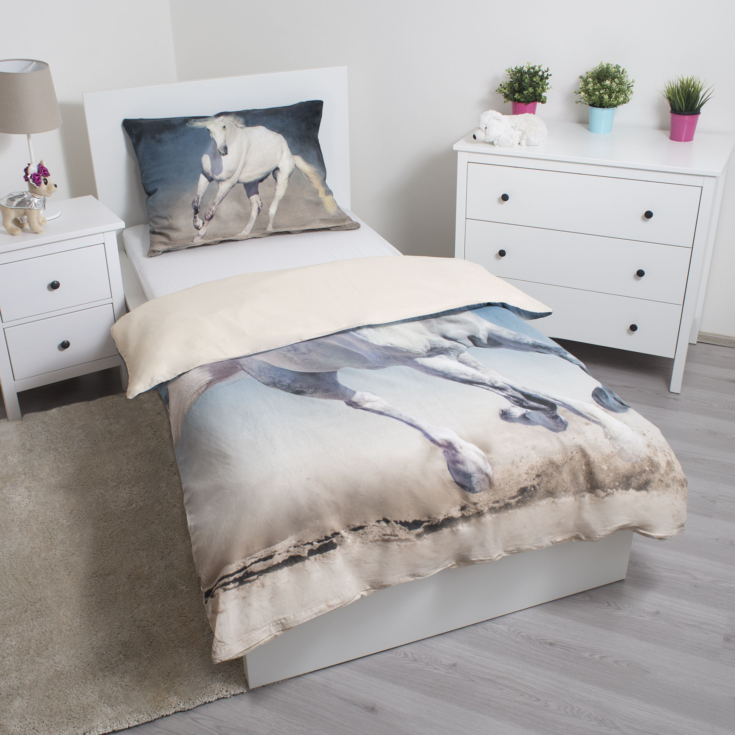Schlafzimmer mit Bett und Pferde-Bettwäsche. Weiße Möbel und ein grauer Teppich vervollständigen die Szene.