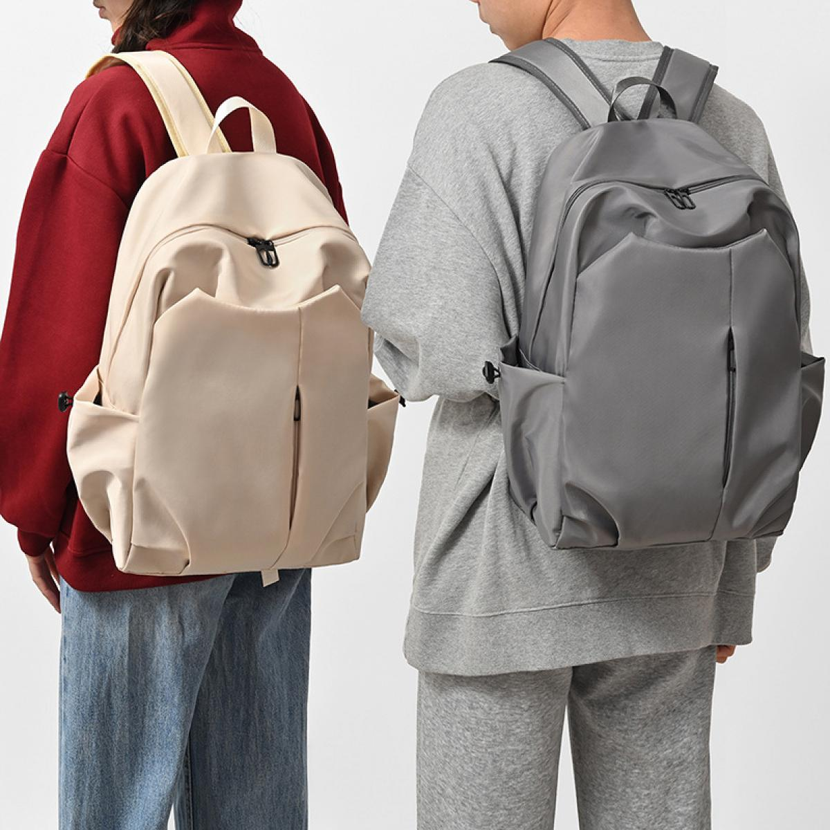 Zwei Personen mit Rucksäcken. Einer beige, der andere grau. Einer trägt einen roten Hoodie, der andere einen grauen Sweatshirt. Weißer Hintergrund.
