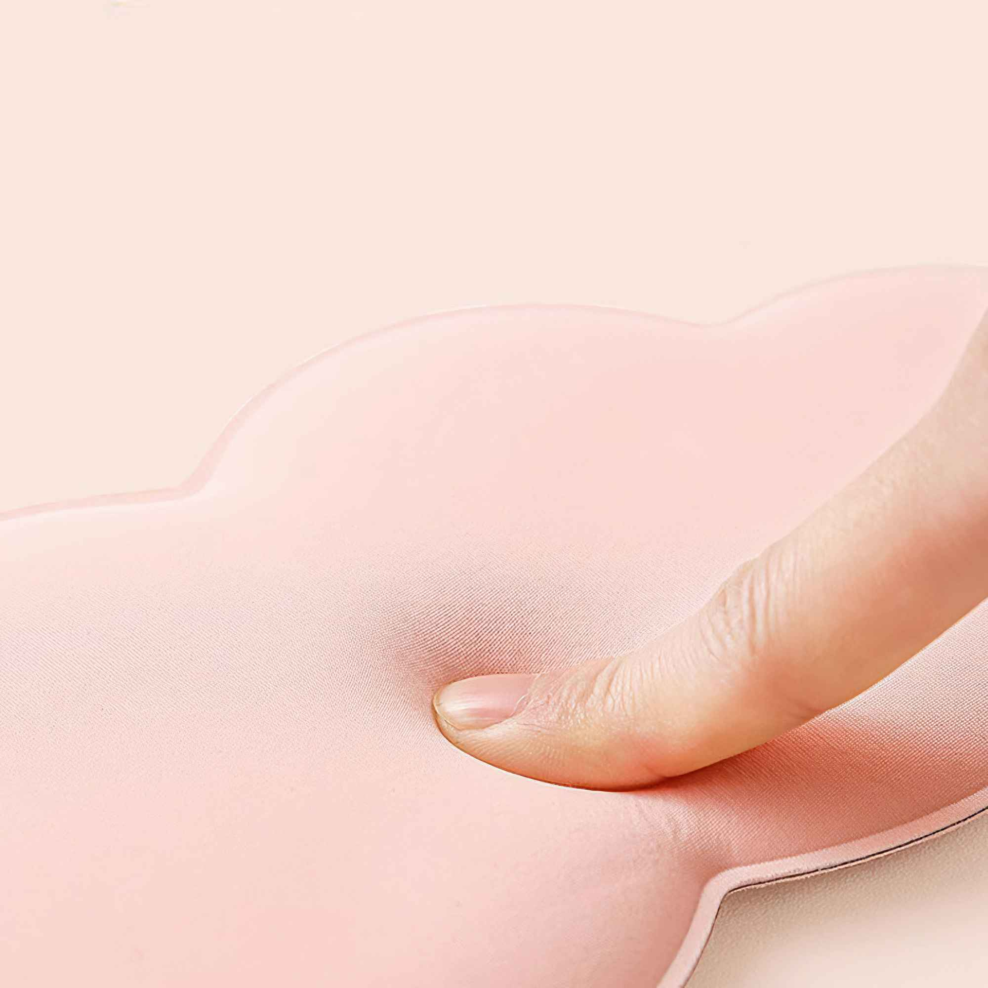 Ein Finger drückt auf ein rosa, wolkenförmiges Objekt. Der Hintergrund ist hellrosa.