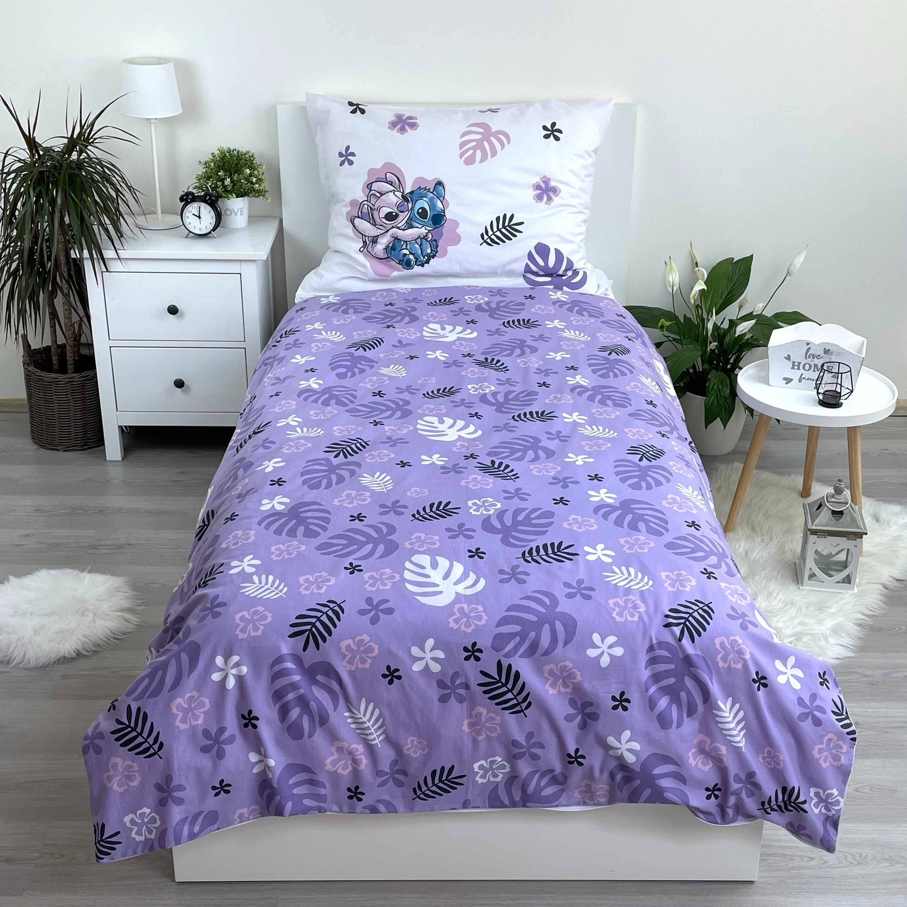Schlafzimmer mit Bett in lila Blumenmuster, Nachttisch und Pflanzen.