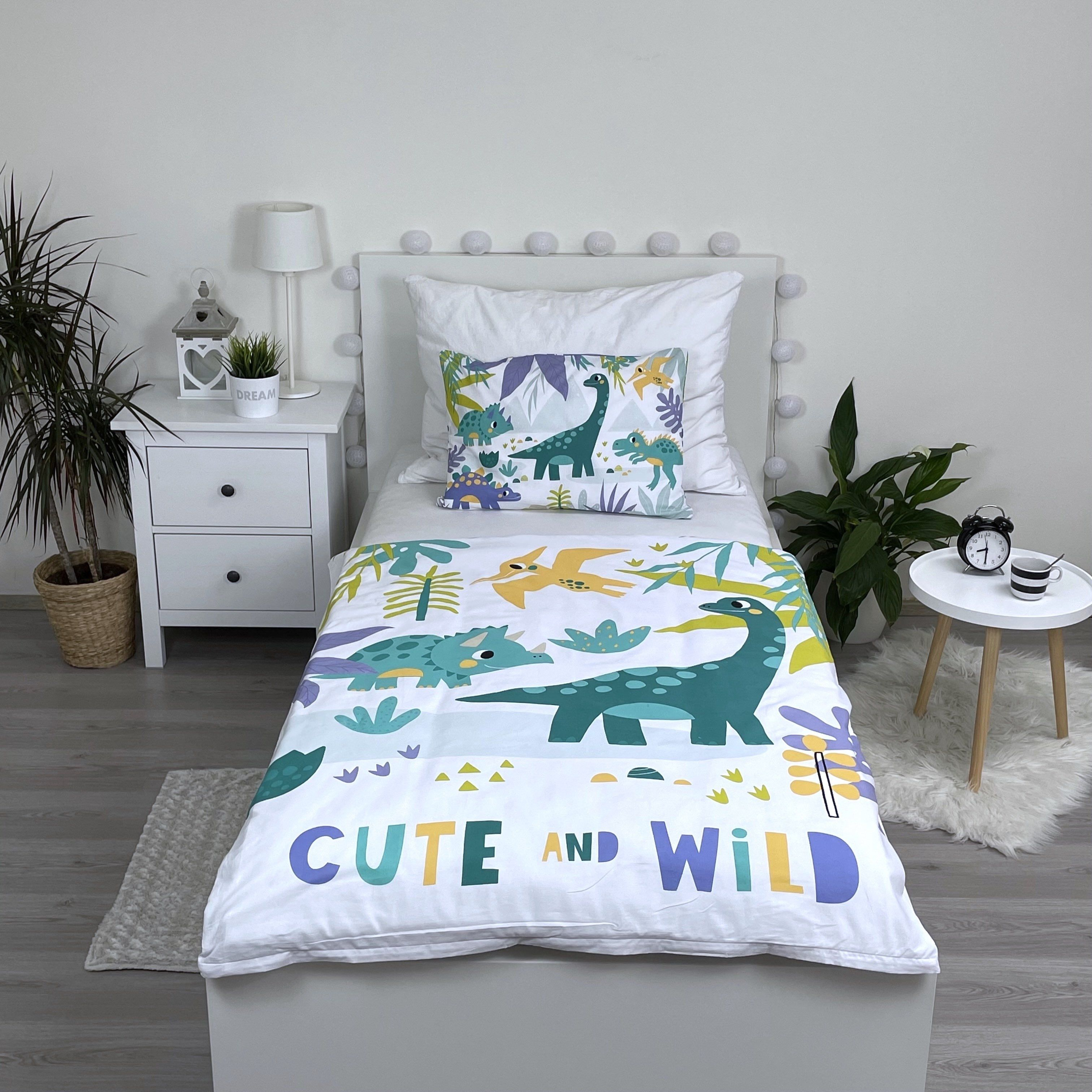 Kinderzimmer mit Bett und Dinosaurier-Bettwäsche. Ein Nachttisch mit Lampe und Uhr ist sichtbar.