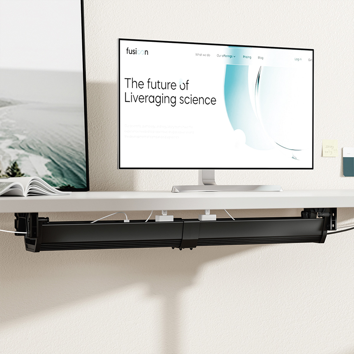 Ein Monitor zeigt eine Website, darunter ein Schreibtisch-Organizer, ein weißer Schreibtisch und eine Wand. Kabel und Haftnotizen sind sichtbar.