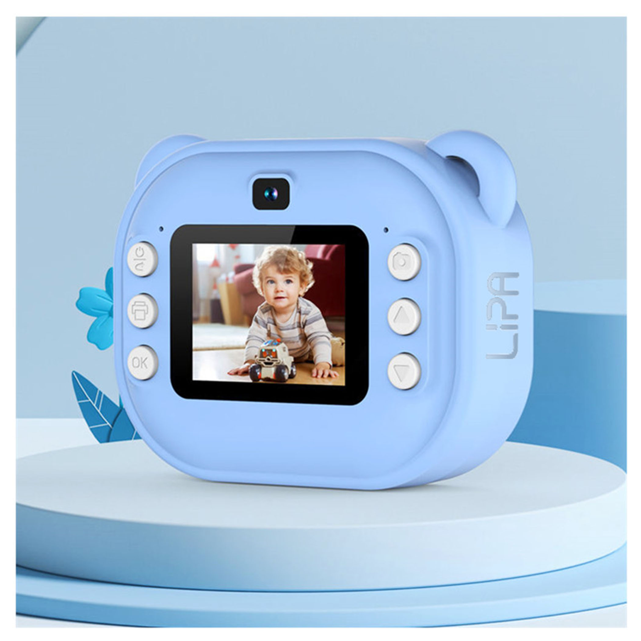 Niebieski aparat dla dziecka z ekranem pokazującym dziecko bawiące się zabawką. Aparat stoi na białej platformie.