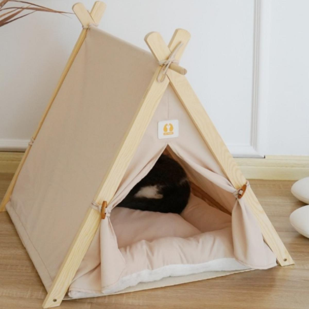 Ein Katzentipi mit beigem Segeltuch und Holzrahmen. Eine schwarz-weiße Katze ist darin. Der Hintergrund ist eine weiße Wand.