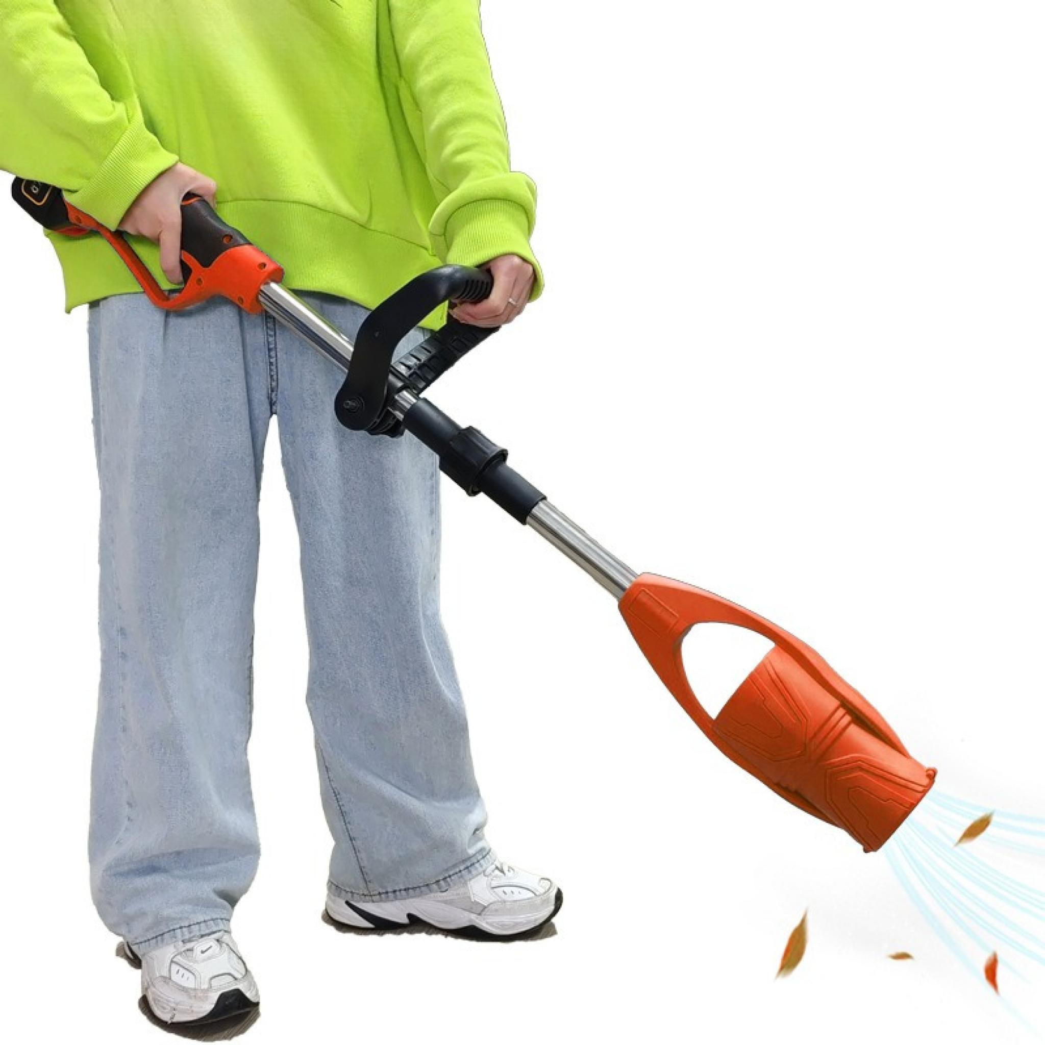 Person hält ein orangefarbenes und schwarzes Laubgebläse. Das Gebläse bläst Blätter. Die Person trägt einen grünen Pullover und Jeans.