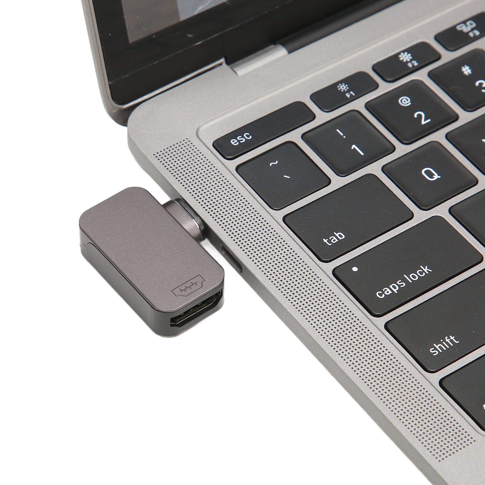 Ein Laptop mit einem grauen HDMI-Adapter. Tastaturtasten sind sichtbar, einschließlich esc, tab, Feststelltaste und Umschalt.