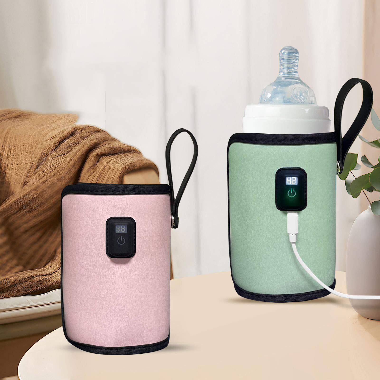 Zwei Babyflaschenwärmer, rosa und grün. Der grüne hat eine Flasche und ist eingesteckt. Beide haben schwarze Griffe.