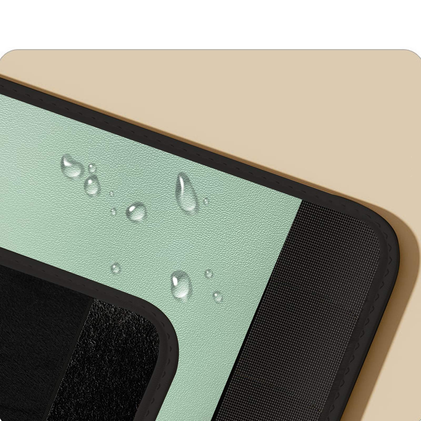 Nahaufnahme einer mintgrünen Oberfläche mit Wassertropfen, einem schwarzen strukturierten Bereich und einem gebogenen schwarzen Rand. Beiger Hintergrund.
