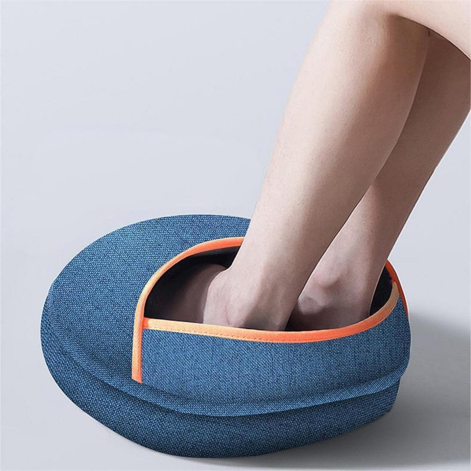 Füße ruhen in einem blauen Fußmassagegerät mit orangefarbenem Rand, Beine darüber. Der Hintergrund ist weiß.