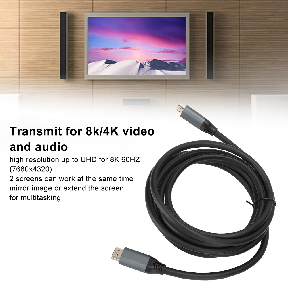 Ein HDMI-Kabel mit grauen Steckern ist auf einer weißen Oberfläche aufgerollt. Ein Fernseher zeigt eine Bergszene, darunter Text.
