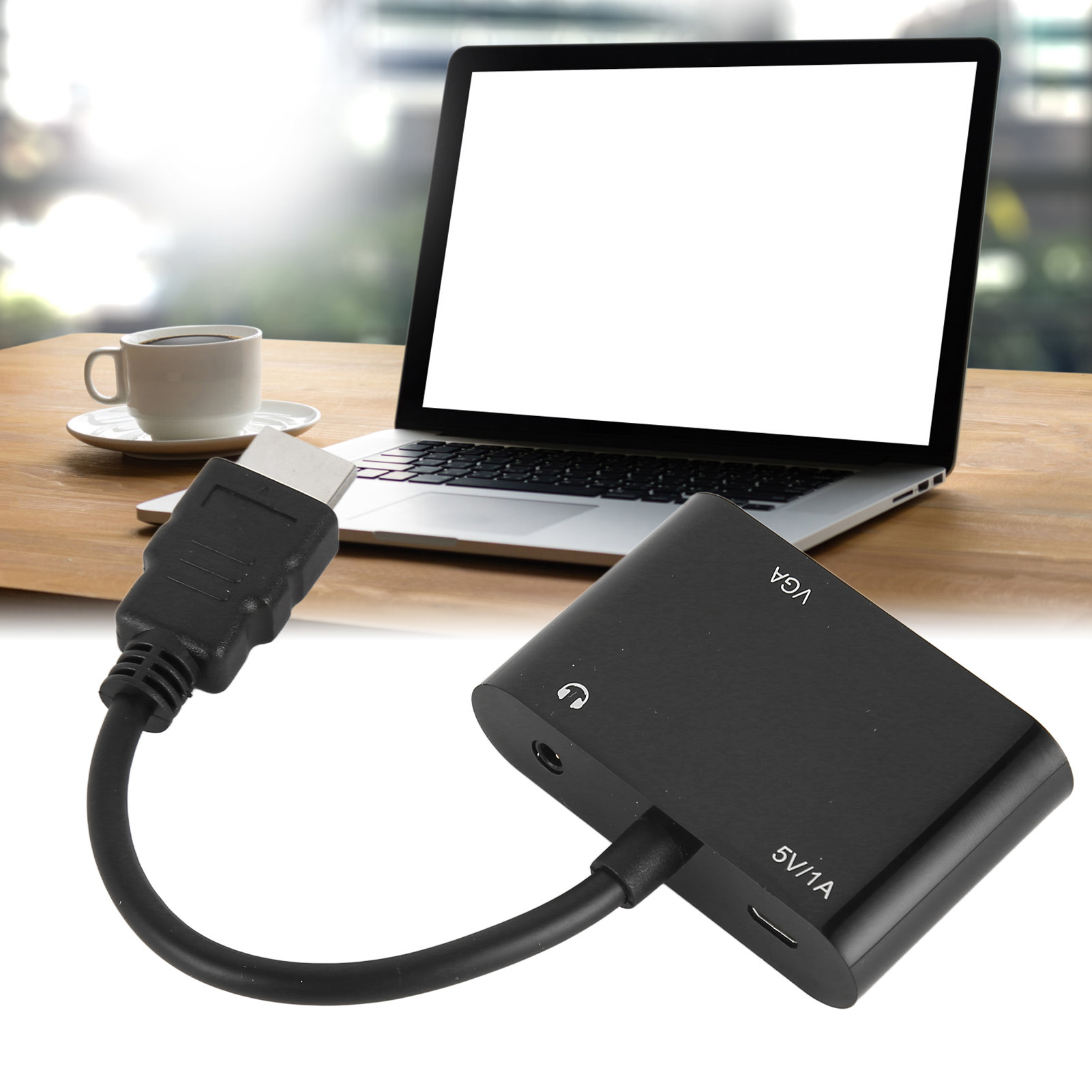 Laptop mit leerem Bildschirm, HDMI-Kabel und schwarzem VGA-Adapter. Eine Tasse Kaffee steht auf einem Holztisch.