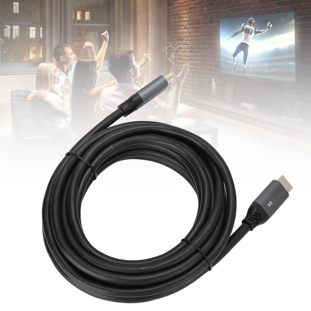 Ein schwarzes HDMI-Kabel im Vordergrund. Im Hintergrund schauen Menschen fern, ein Footballspieler ist auf dem Bildschirm.