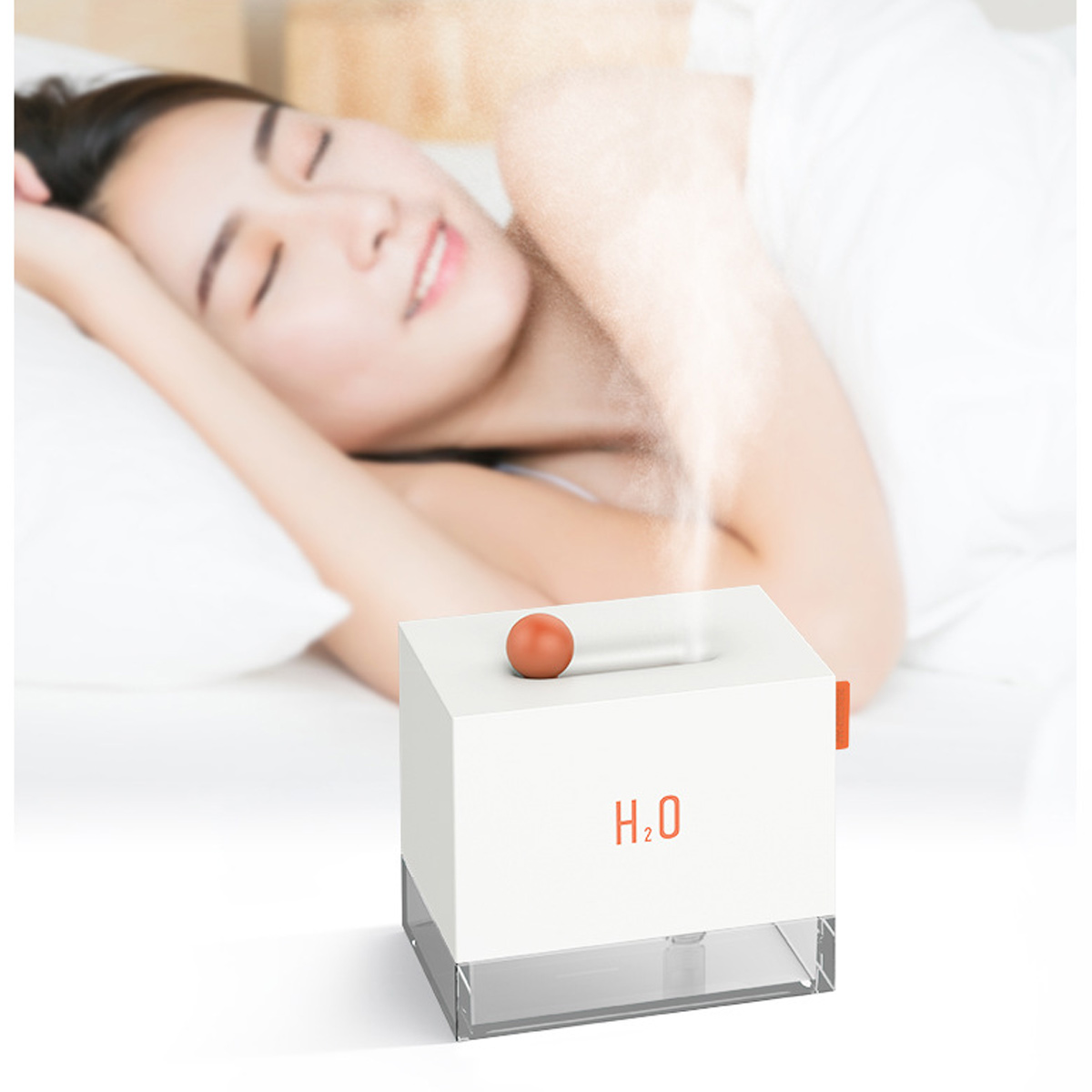 Eine Frau schläft im Bett. Ein weißer Luftbefeuchter mit einer orangefarbenen Kugel oben und dem Text H2O befindet sich im Vordergrund. Dampf steigt auf.
