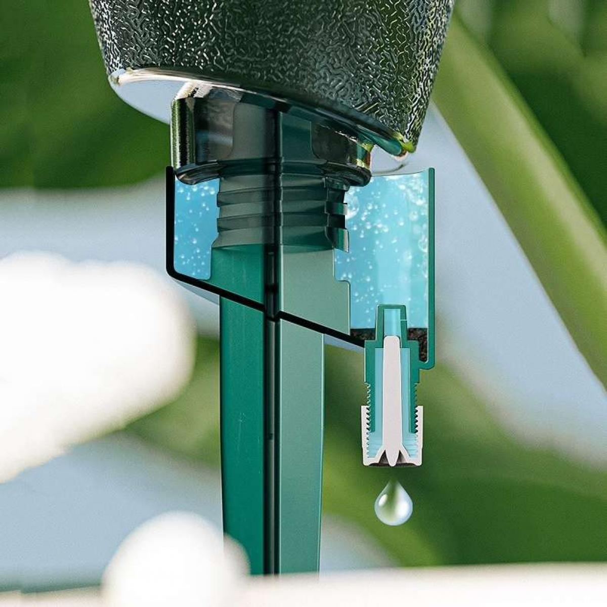 Nahaufnahme eines grünen Wasserbewässerungssystems. Ein Wassertropfen fällt. Der Hintergrund zeigt verschwommenes grünes Laub.