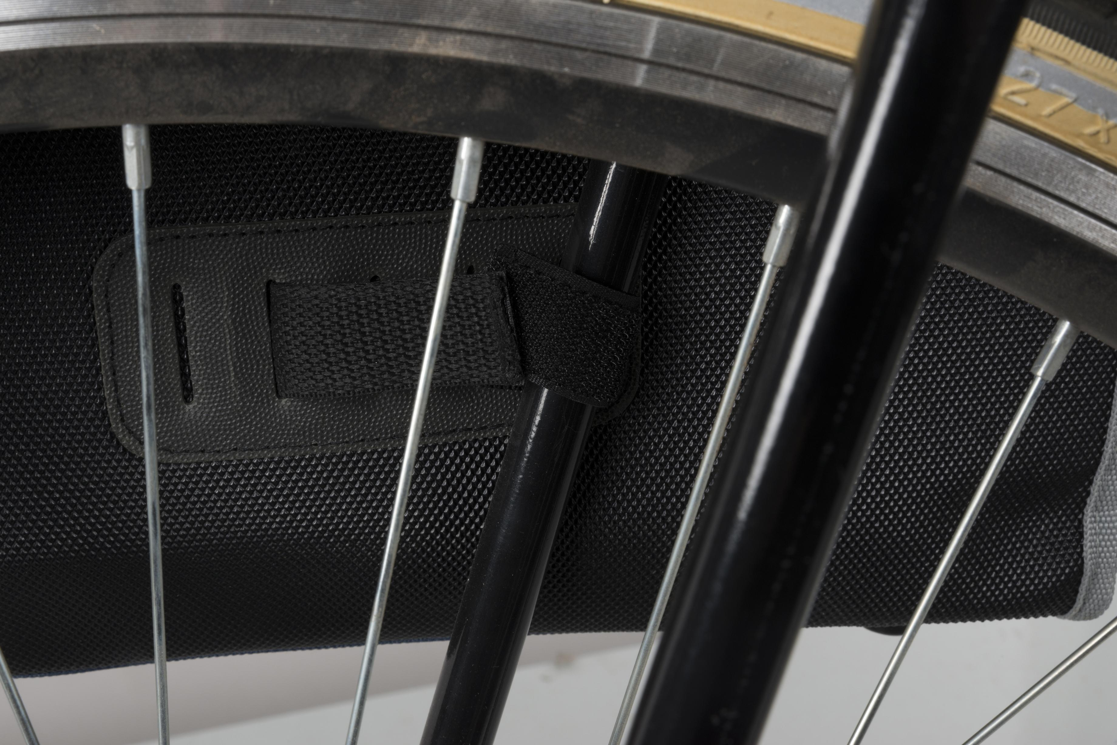 Close-up van een fietswiel met spaken, een zwarte fietstas aan het frame en een deel van de band.