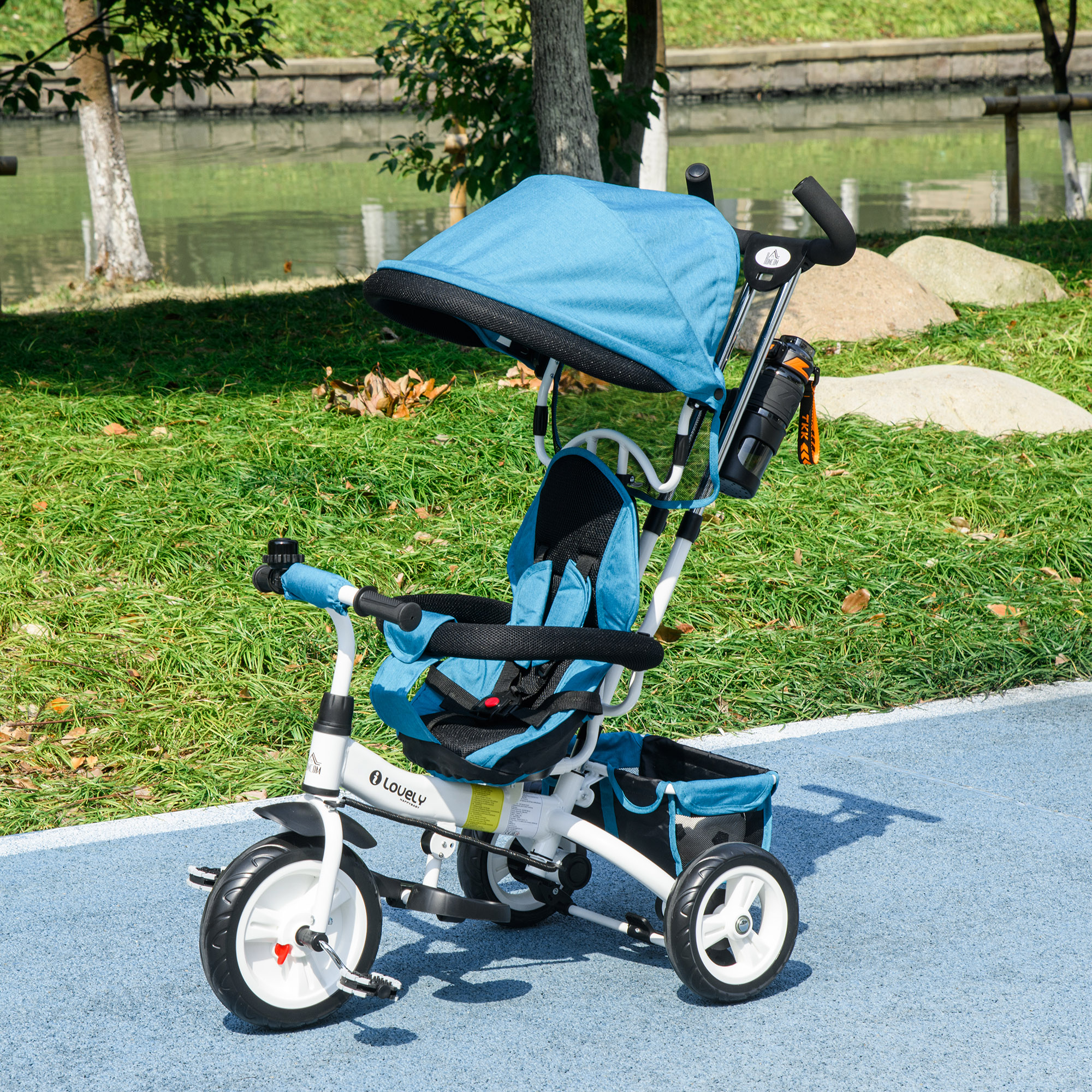 Un triciclo blu e bianco con tettuccio si trova su una superficie blu, con verde e acqua sullo sfondo.