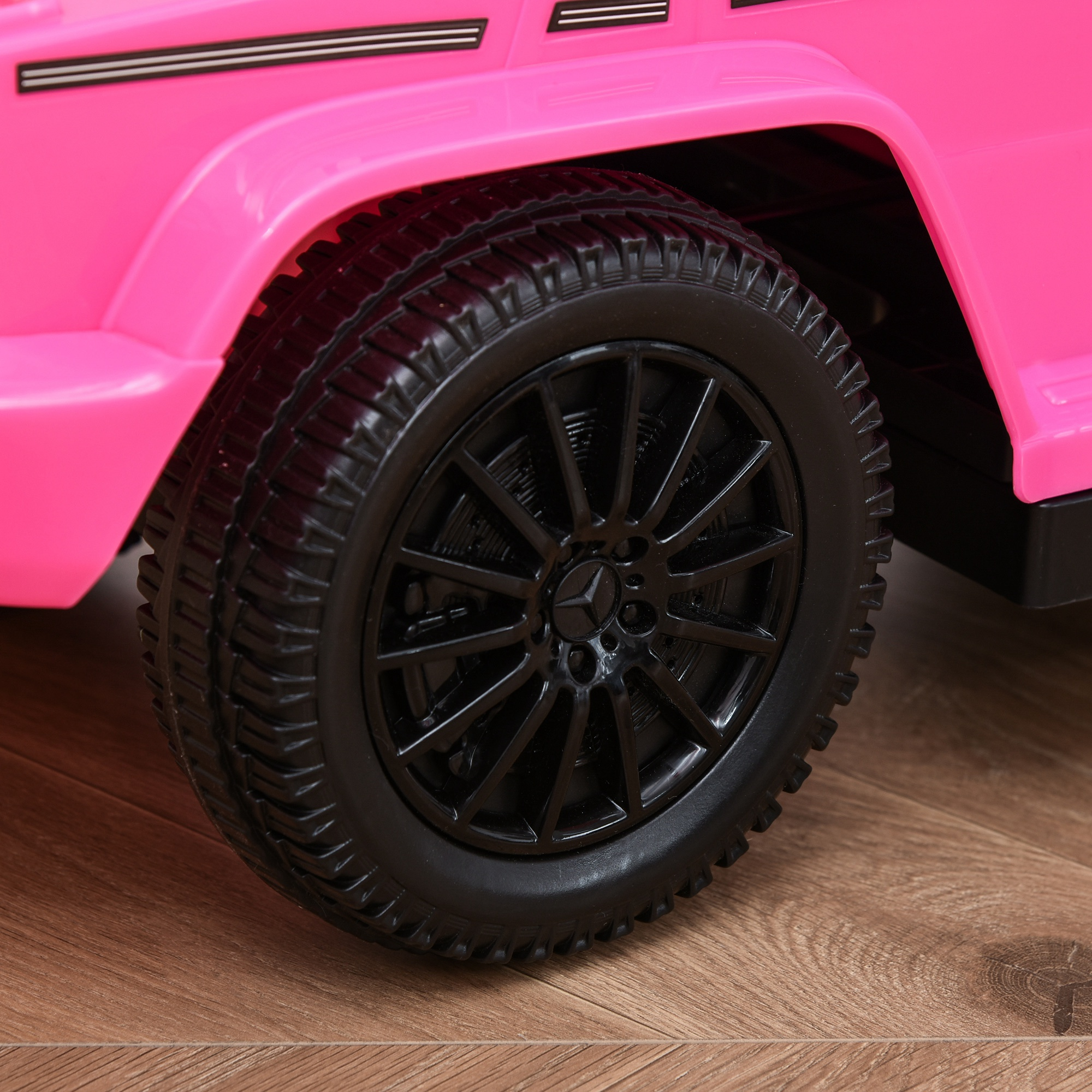 Primo piano dello pneumatico di un'auto giocattolo rosa. Lo pneumatico nero ha un battistrada dettagliato. È visibile un cerchio nero.