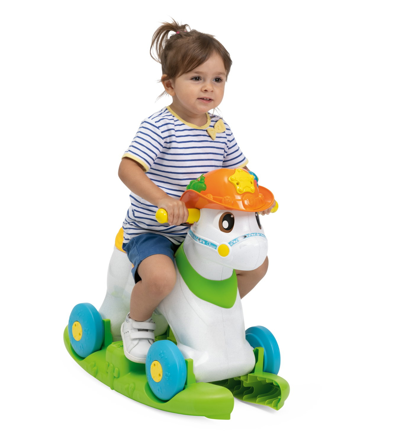Un bambino piccolo cavalca un cavallo giocattolo bianco e verde con un cappello arancione. Il bambino indossa una maglietta a righe e pantaloncini blu.