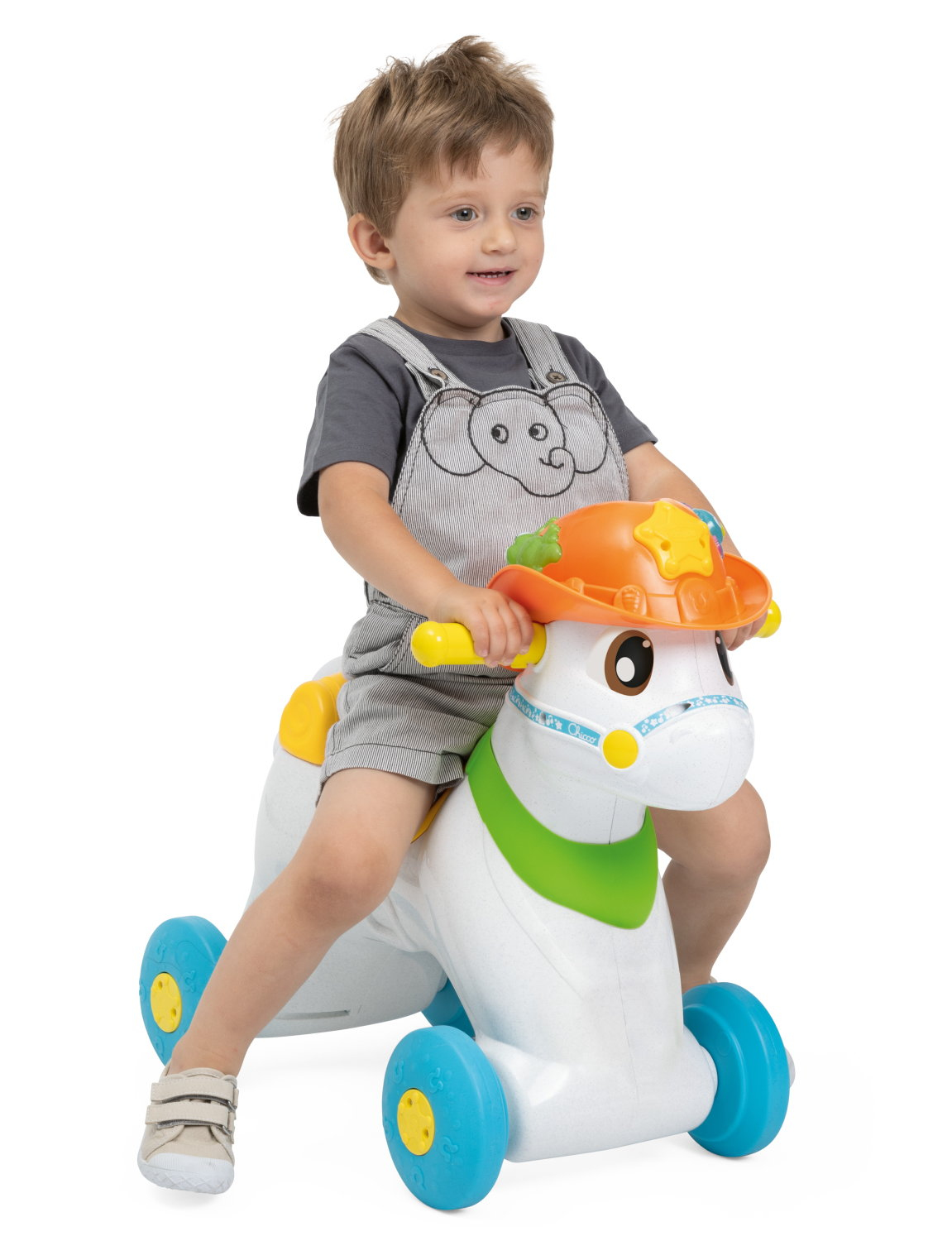 Un bambino cavalca un cavallo giocattolo bianco e blu. Indossa un completo grigio. Il cavallo ha un cappello arancione.