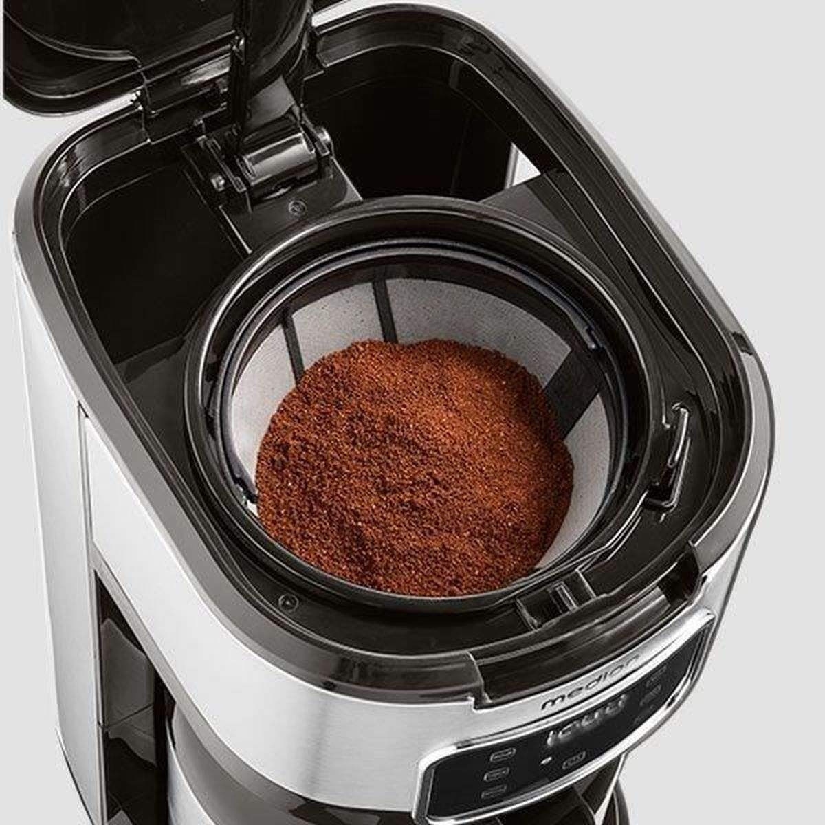 Macchina da caffè con coperchio aperto. Visibile filtro con caffè macinato. La macchina è nera, argento e bianca.