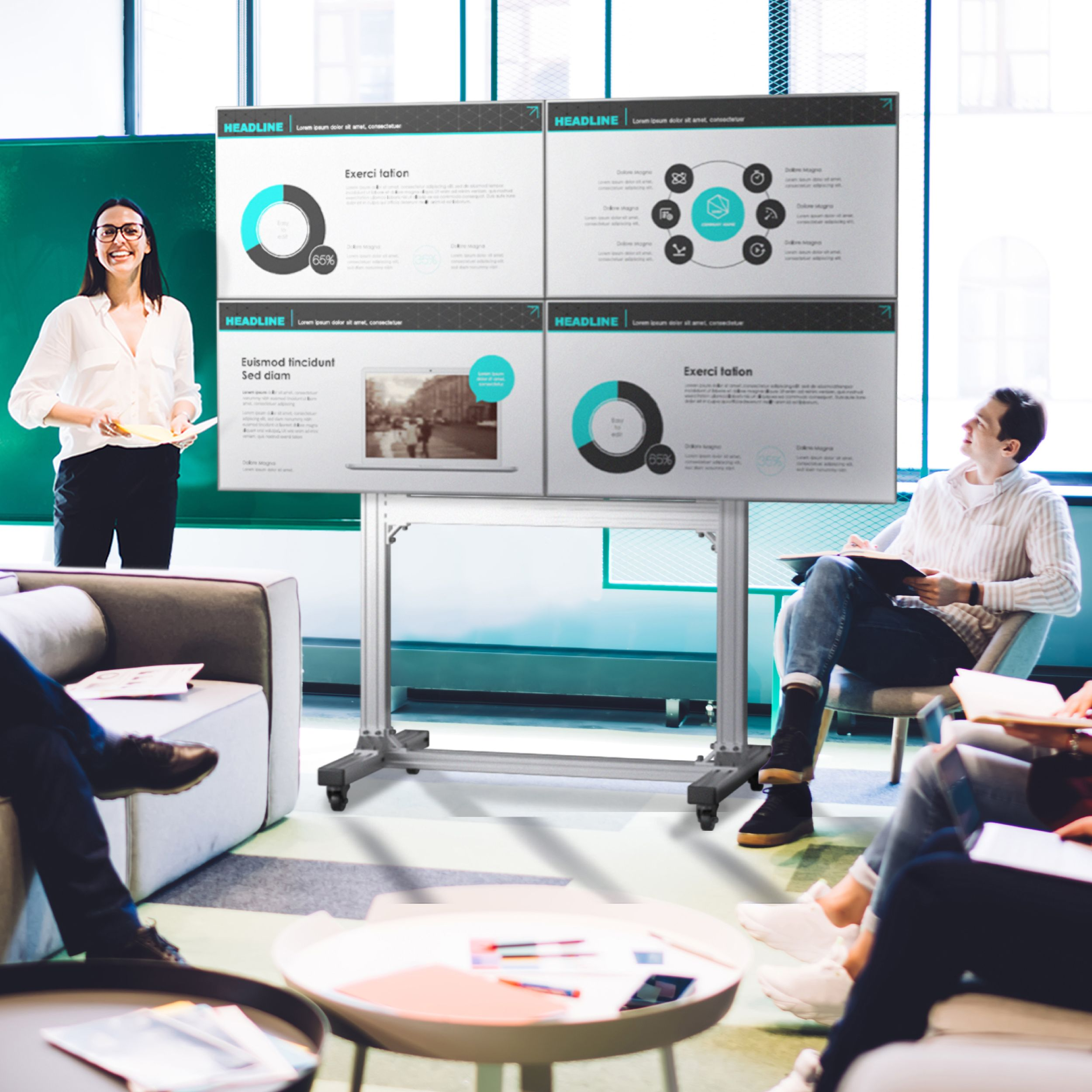 Frau mit Brille präsentiert einer Gruppe. Präsentationsbildschirme zeigen Diagramme. Personen sitzen in einem modernen Büroumfeld.