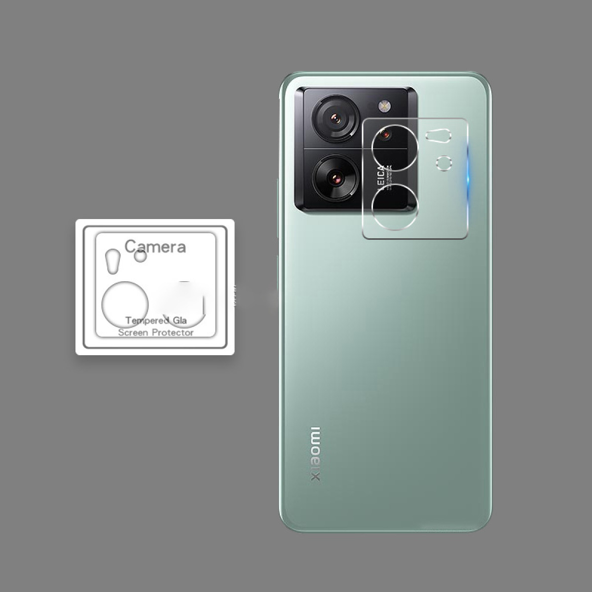 Un telefono Xiaomi verde menta con protezione per la fotocamera. Il telefono ha un modulo fotocamera e una protezione schermo. Visibile una scatola di protezione fotocamera.