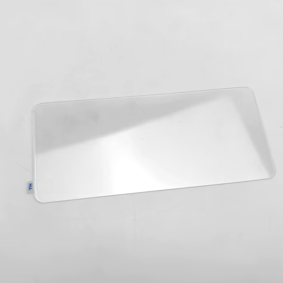 Przezroczysty, prostokątny kawałek plastiku jest ustawiony pod kątem na białej powierzchni. Niebieska naklejka z napisem "YH" znajduje się w lewym dolnym rogu.