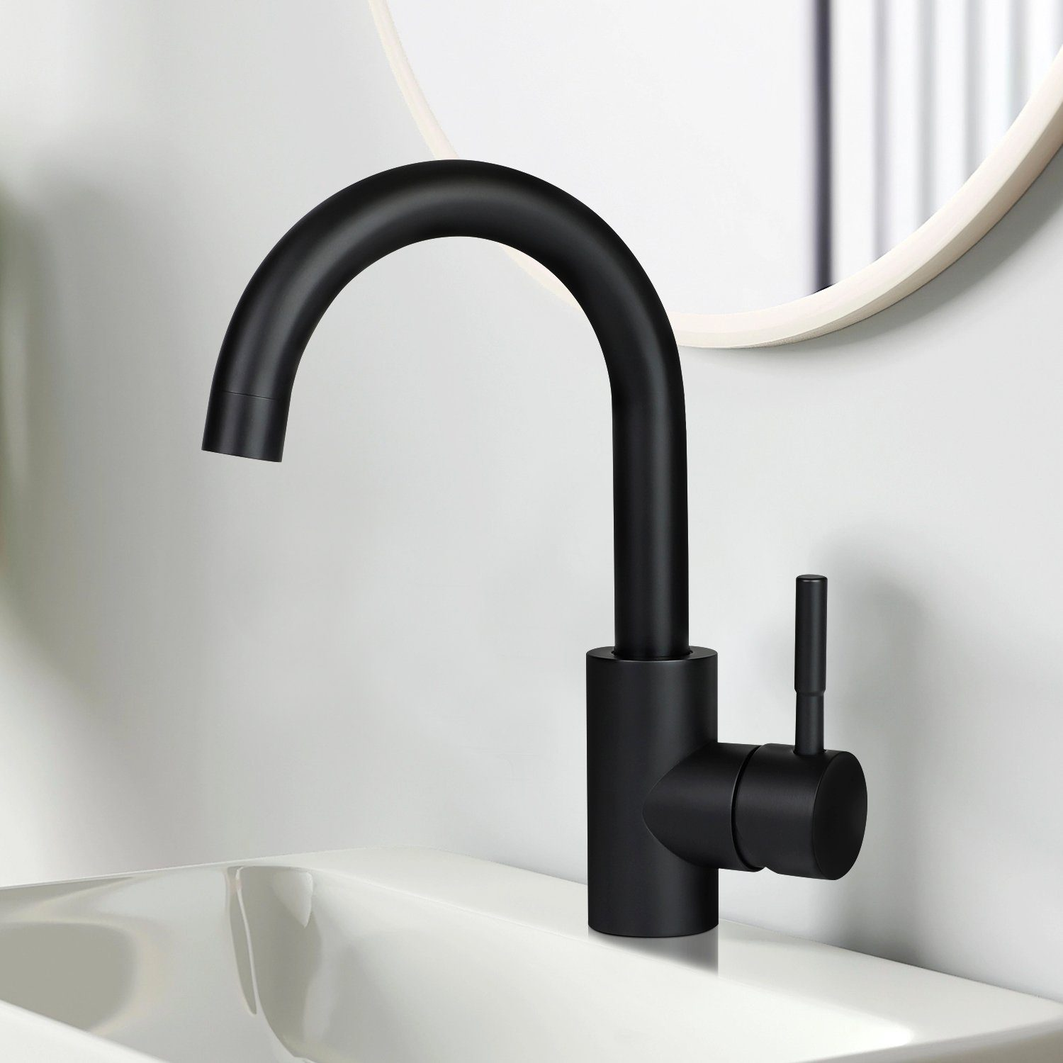 Czarna bateria zamontowana na białym zlewie. W tle okrągłe lustro. Bateria ma zakrzywioną wylewkę i dźwignię.