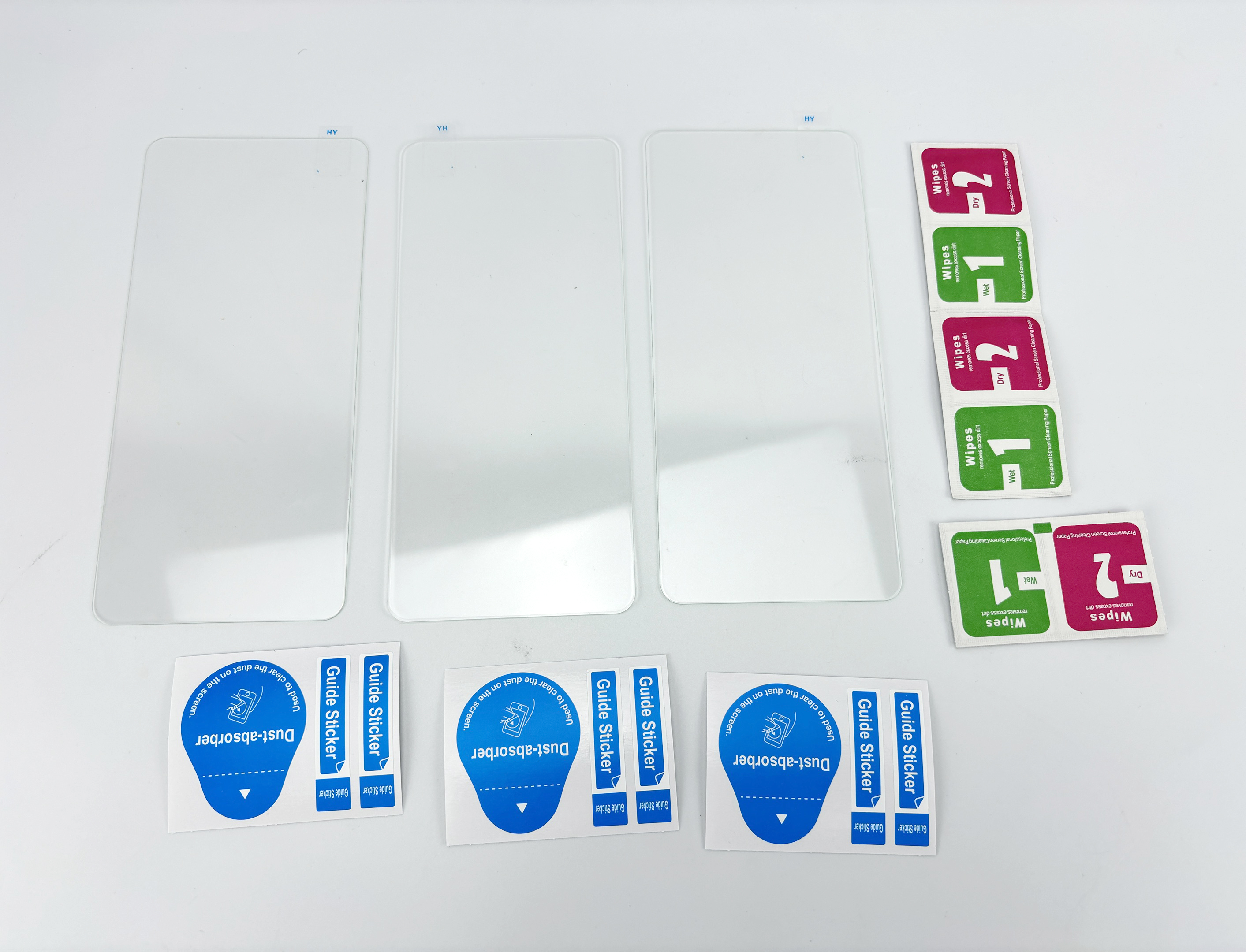 Obraz przedstawia trzy osłony ekranu, chusteczki i naklejki na białej powierzchni. Widoczne są etykiety i instrukcje.