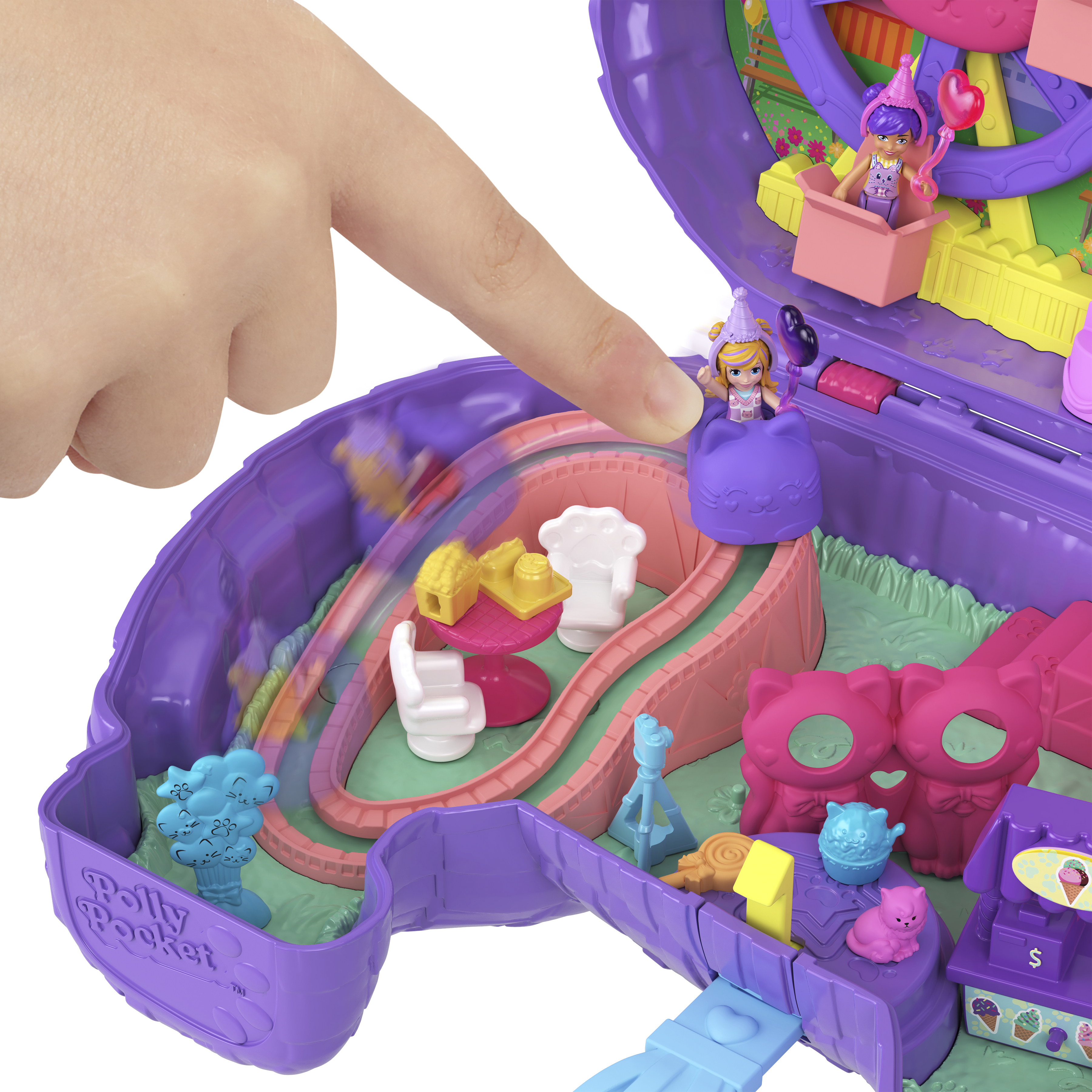 Dłoń dotyka zabawki Polly Pocket. Zawiera diabelski młyn, zjeżdżalnie i miniaturowe figurki w fioletowym zestawie.