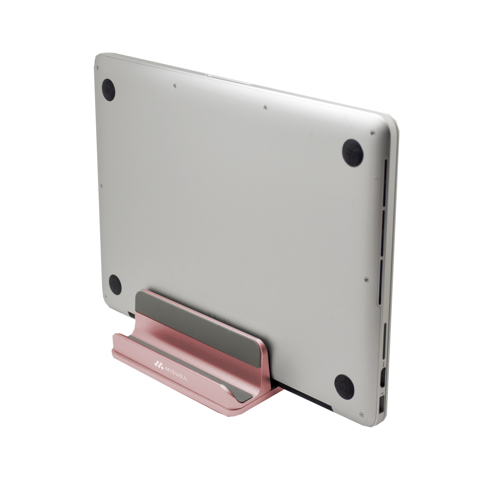 Un laptop argentato poggia su un supporto rosa. Il supporto ha un cuscinetto grigio. La parte posteriore del laptop è visibile, con punti neri.