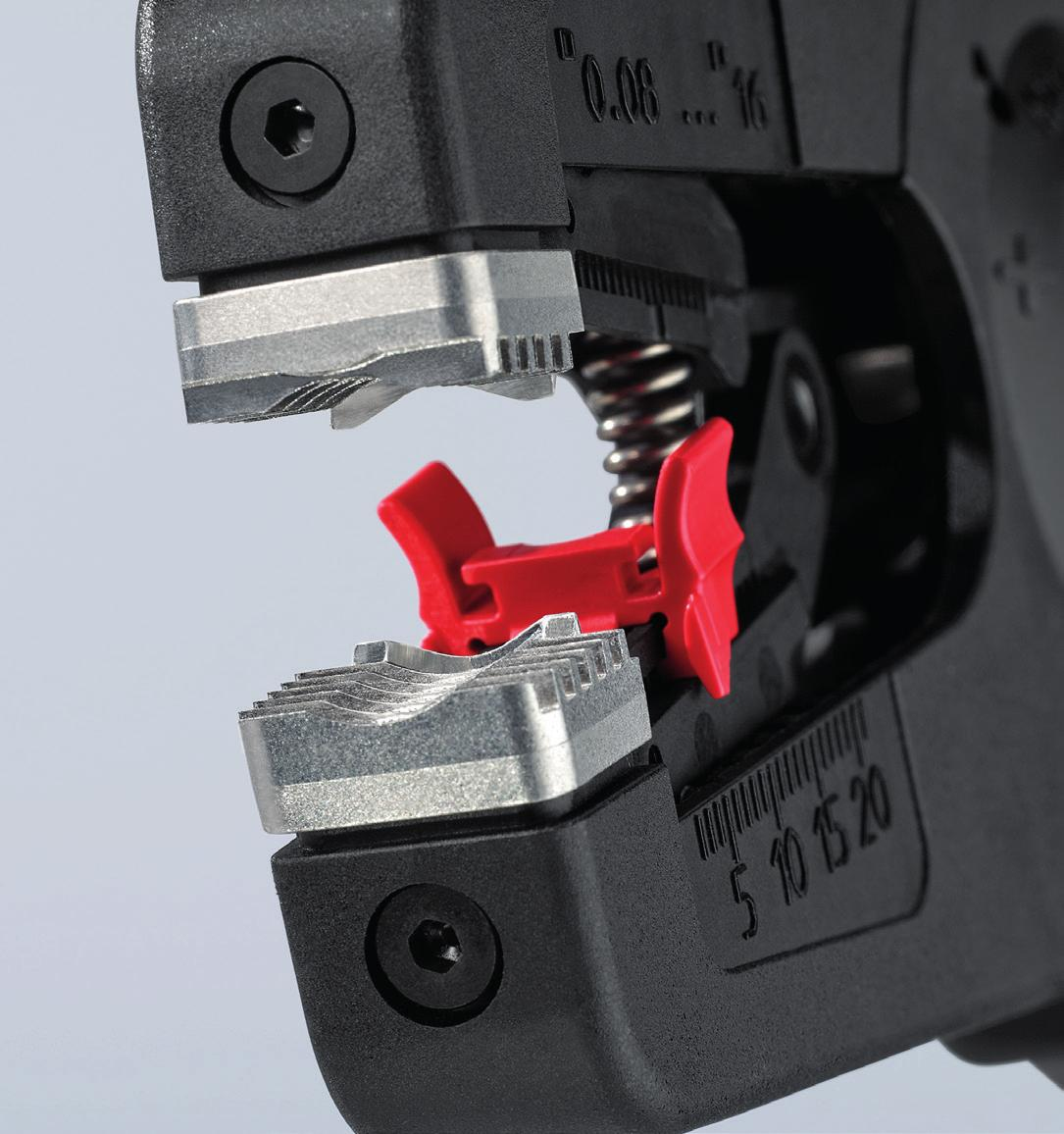 Zbliżenie ściągacza izolacji. Czarne i srebrne narzędzie z czerwonym elementem z tworzywa sztucznego. Widoczne cyfry.