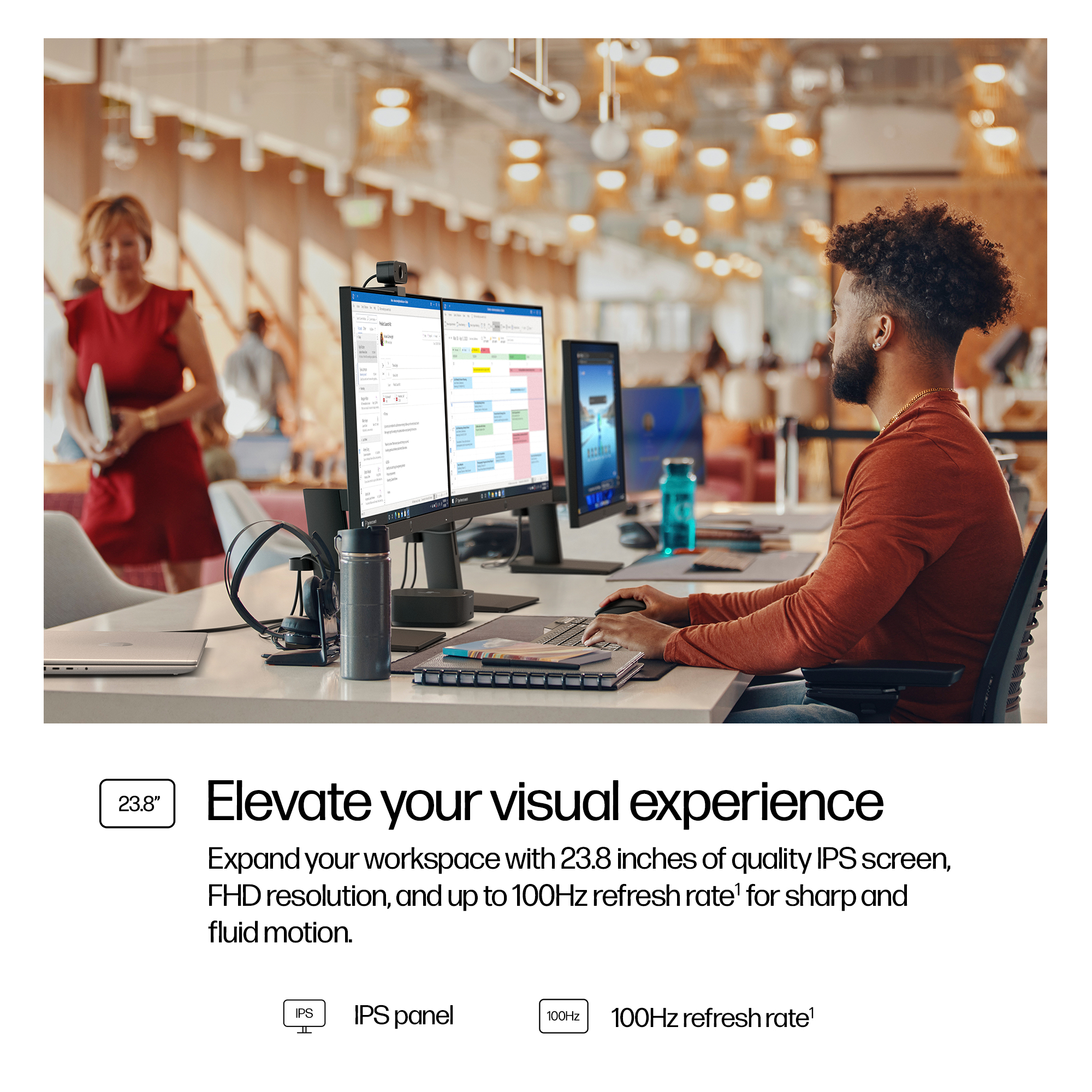 Un uomo lavora a una scrivania con due monitor. Una donna in rosso cammina sullo sfondo. L'immagine promuove le funzionalità di un monitor.