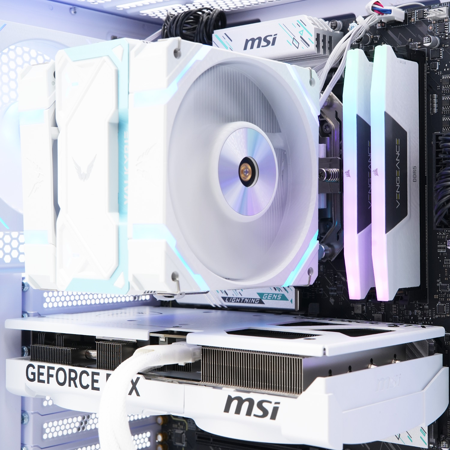 Dentro de una carcasa de computadora blanca, los componentes incluyen una tarjeta gráfica MSI blanca, un enfriador de CPU y memorias RAM, todos con luces LED.