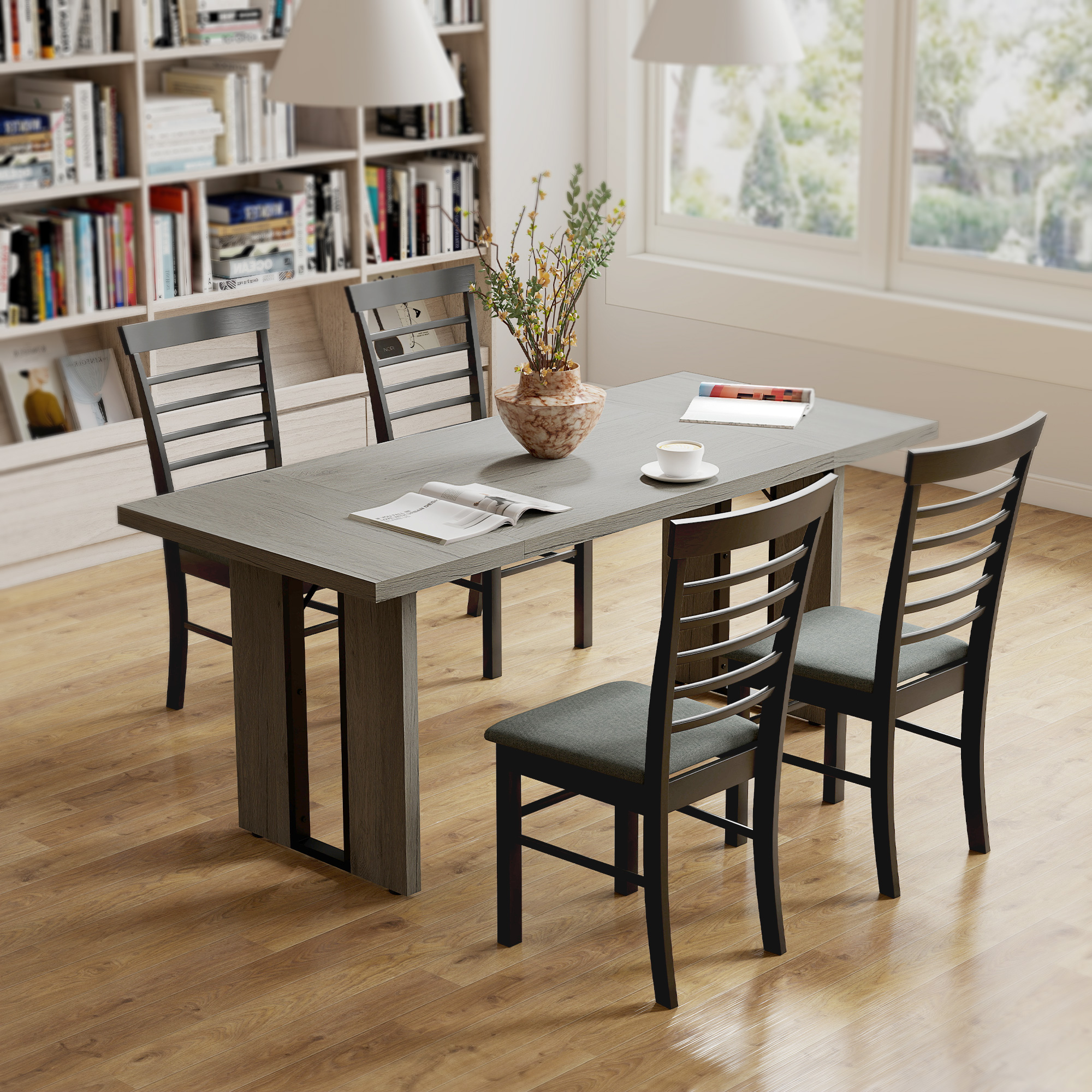 Una sala da pranzo con un tavolo grigio, quattro sedie, un vaso di fiori e una libreria sullo sfondo.
