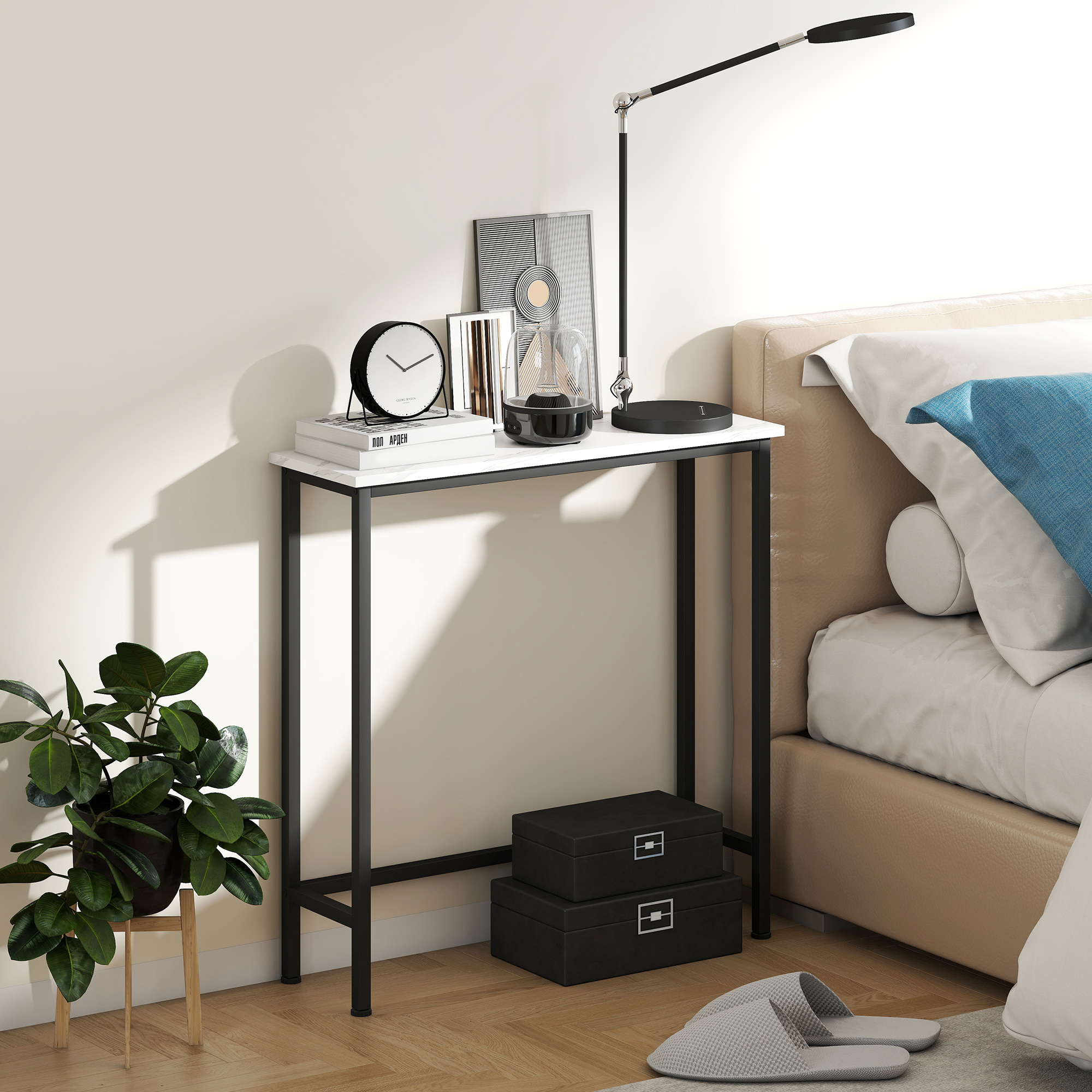 Un comodino con lampada, orologio e decorazioni. Un letto a destra. Una pianta in vaso e due scatole a sinistra.