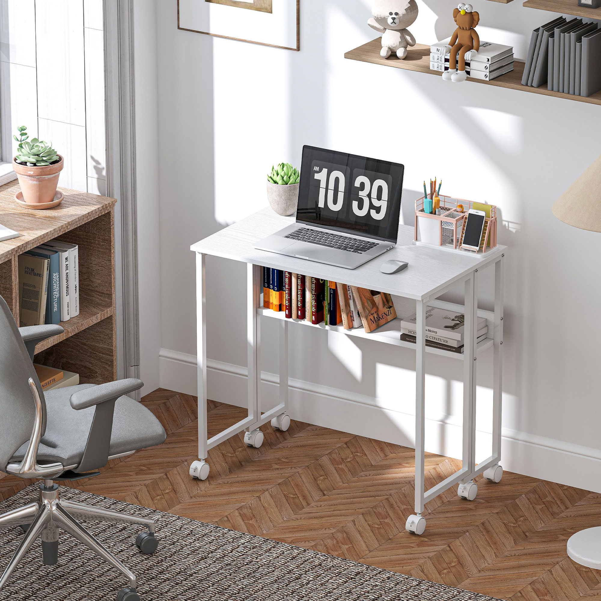 Una scrivania bianca con laptop (10:39), libri, una pianta e forniture per ufficio. Visibili sedia grigia e pavimento in legno.