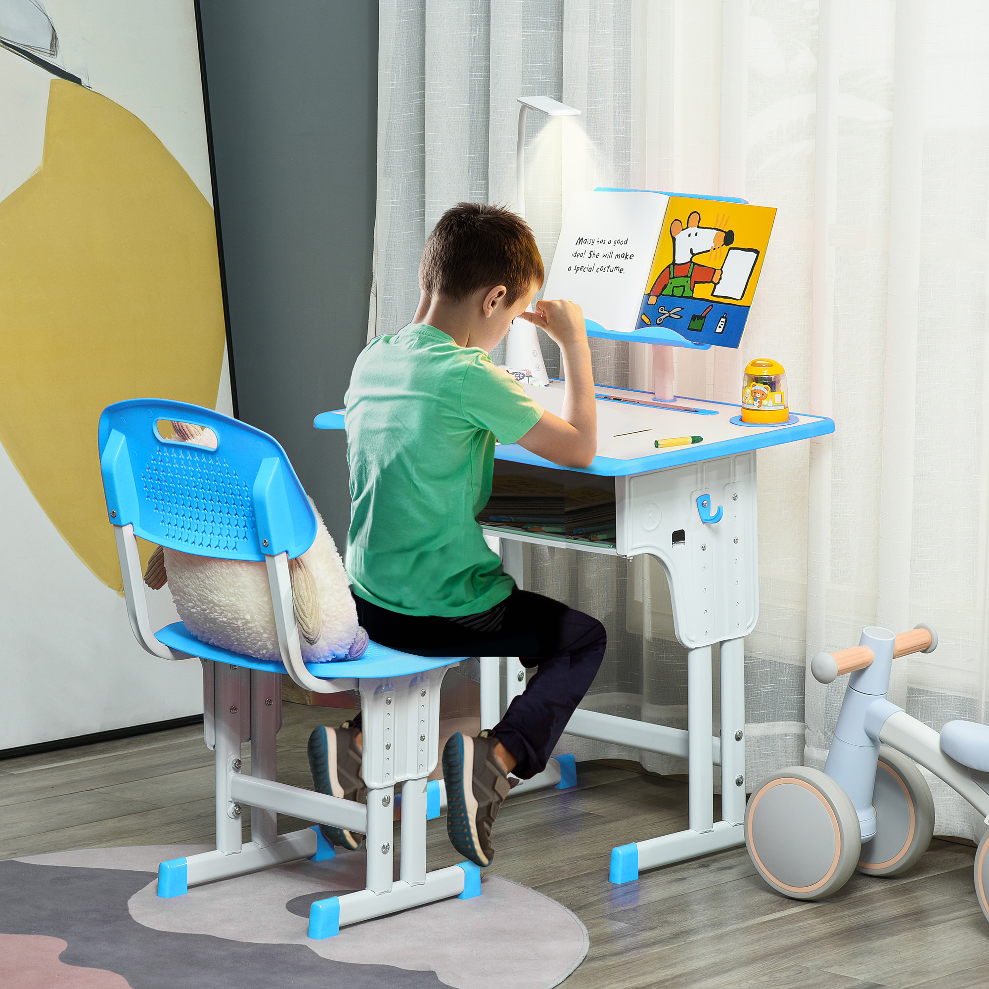 Un bambino è seduto a una scrivania che legge un libro. La scrivania ha una lampada e si vede un giocattolo. C'è una sedia blu dietro il bambino.