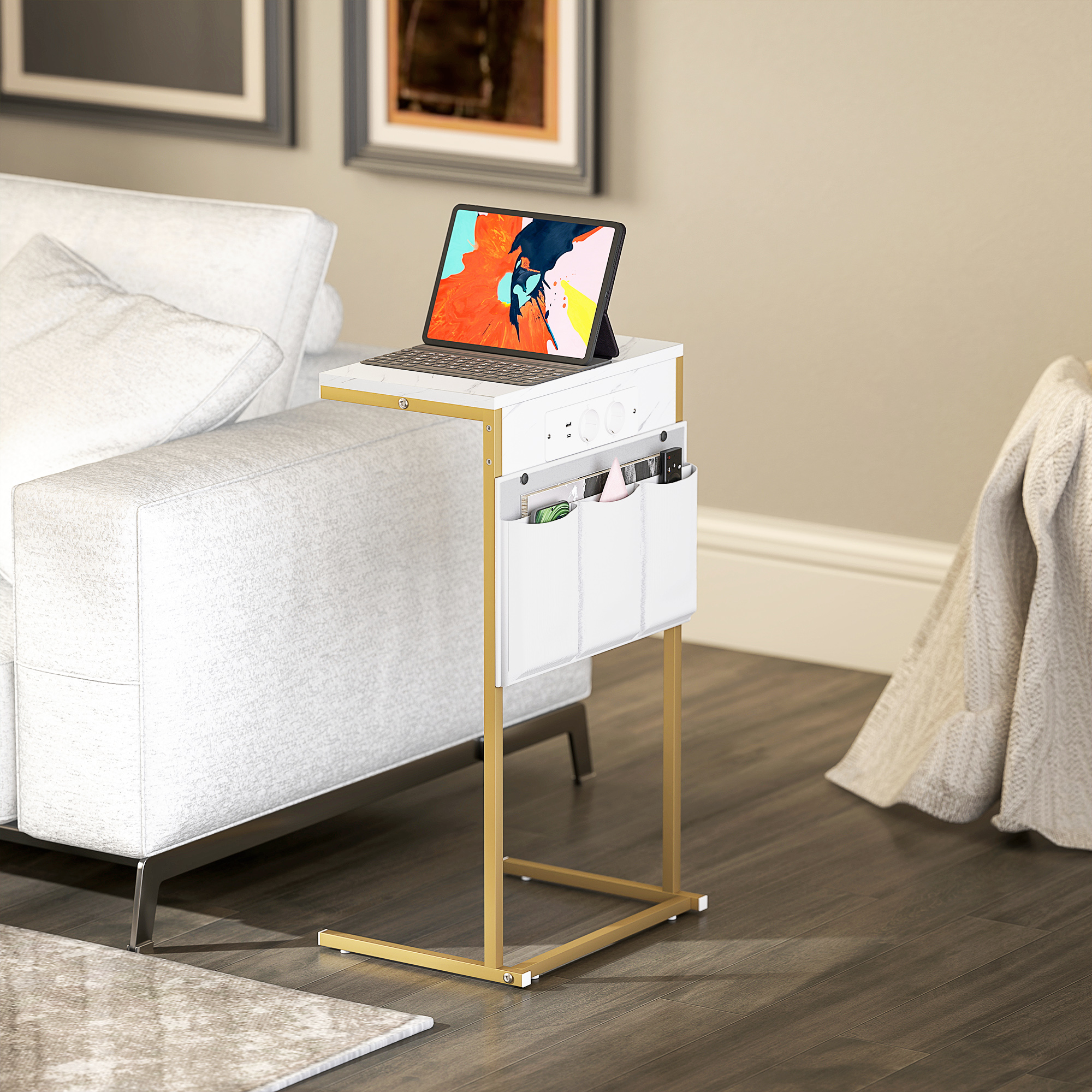Un tavolino bianco con gambe dorate accanto a un divano bianco. Un tablet con tastiera è sul tavolo, con tasche per riporre oggetti.