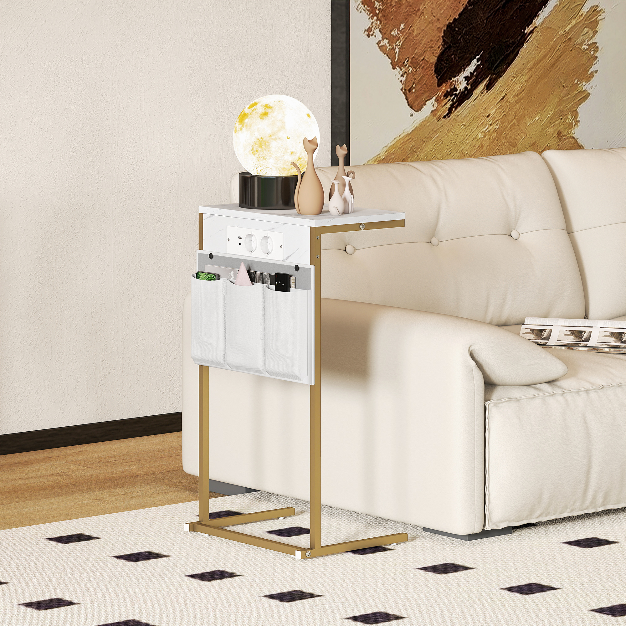 Un tavolino bianco con gambe dorate accanto a un divano bianco. Ha una lampada, statuine di gatto e tasche.