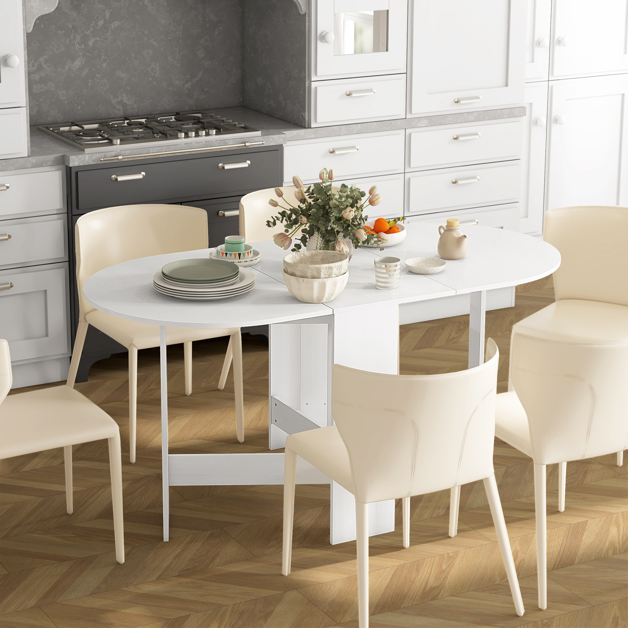 Una cucina bianca con un tavolo apparecchiato. Ci sono sedie beige, un fornello e armadi. Fiori e frutta sul tavolo.
