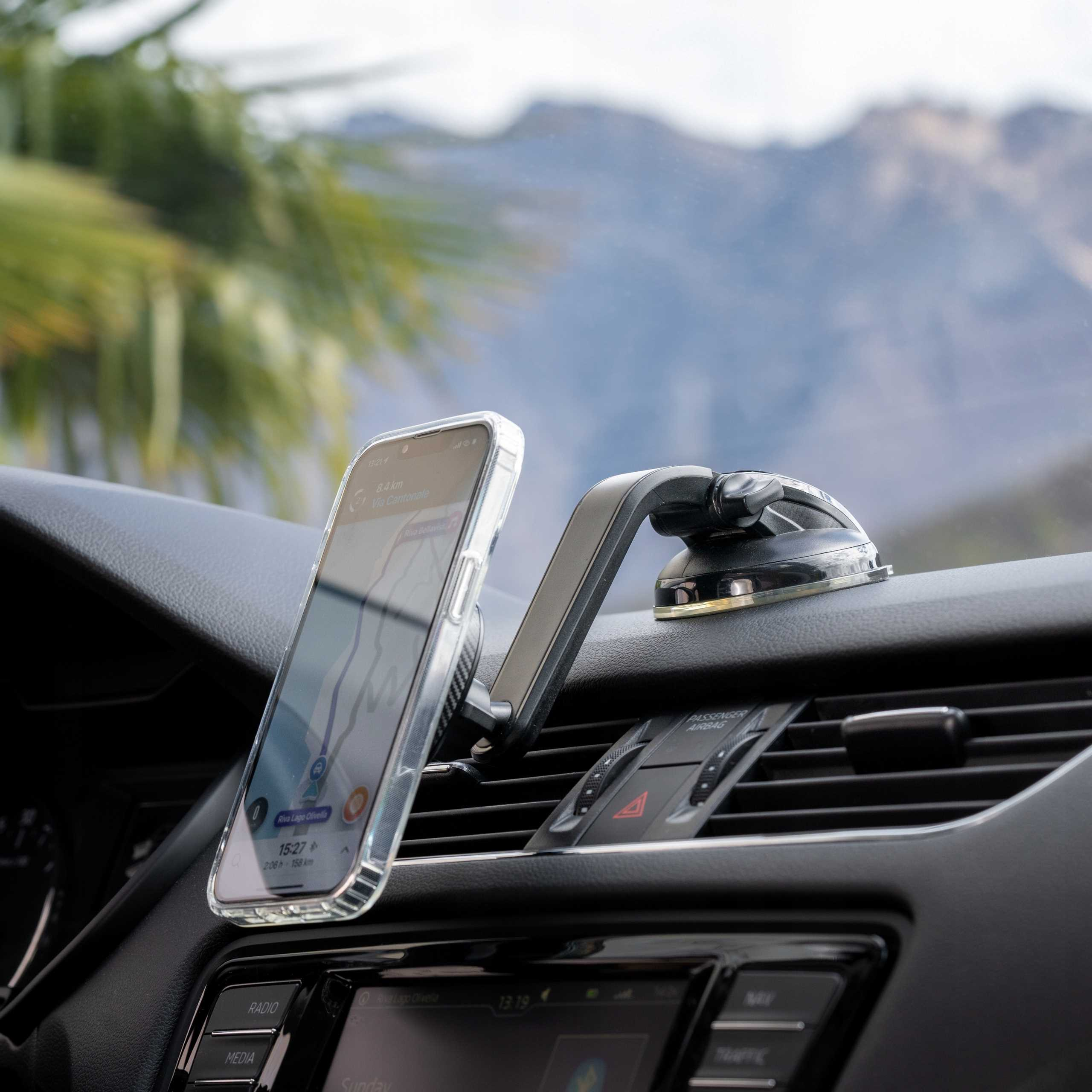 Telefon z nawigacją zamontowany w samochodzie. W tle góry. Deska rozdzielcza i detale samochodu w ostrości.