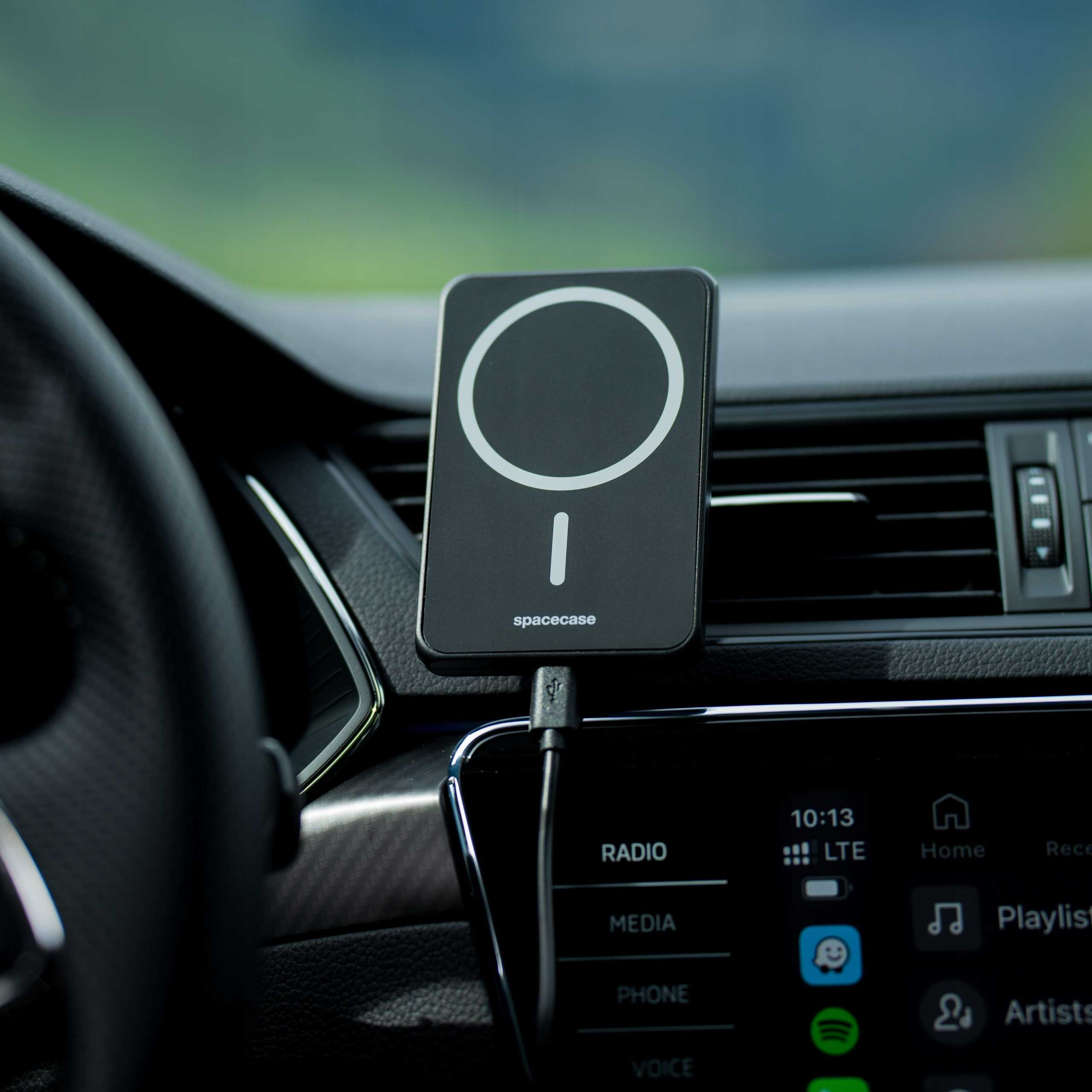 Czarna ładowarka bezprzewodowa Spacase w samochodzie. Widoczna deska rozdzielcza i kierownica.
