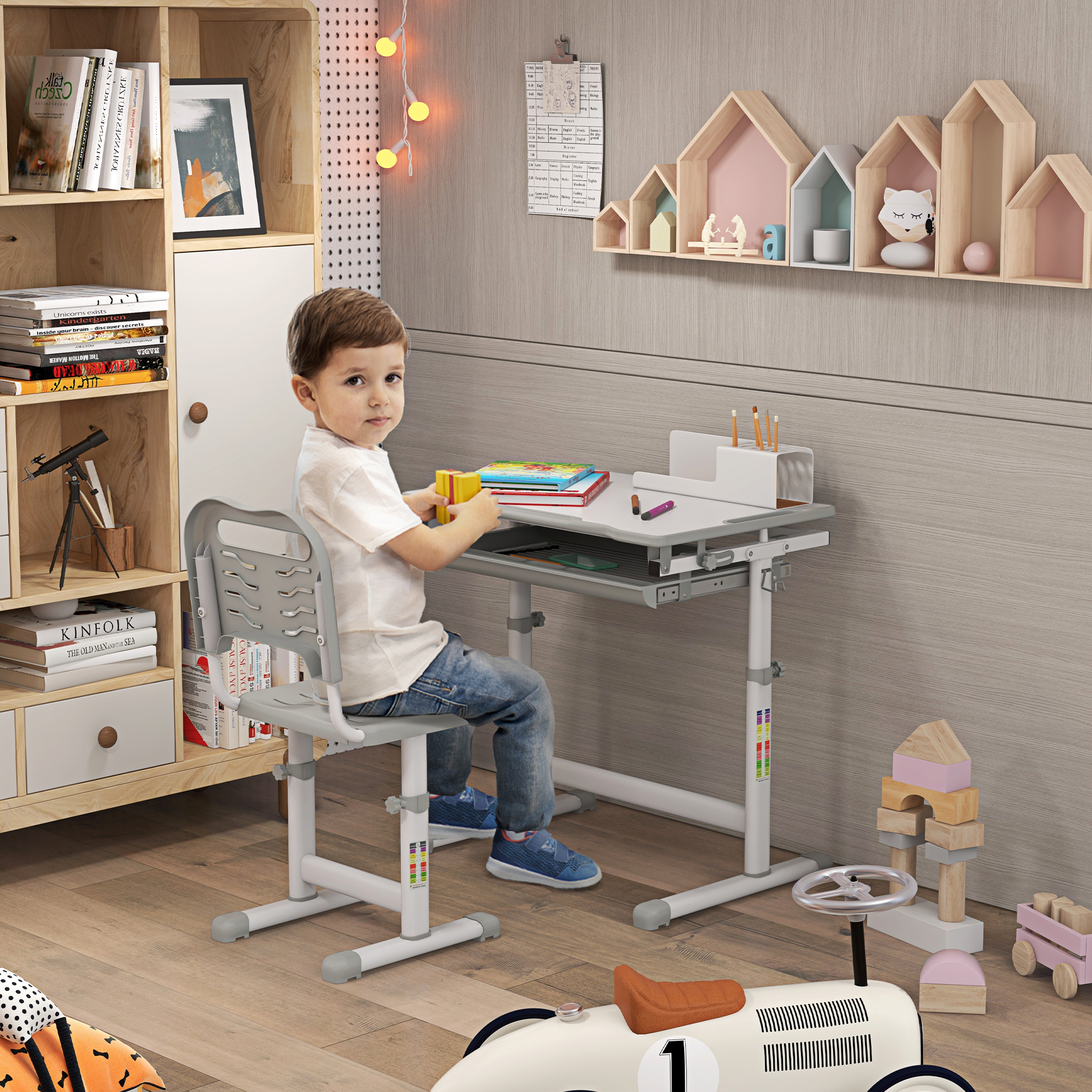 Un bambino è seduto a una scrivania. Sullo sfondo ci sono libri, una lampada e giocattoli. Il bambino indossa jeans e una camicia bianca.