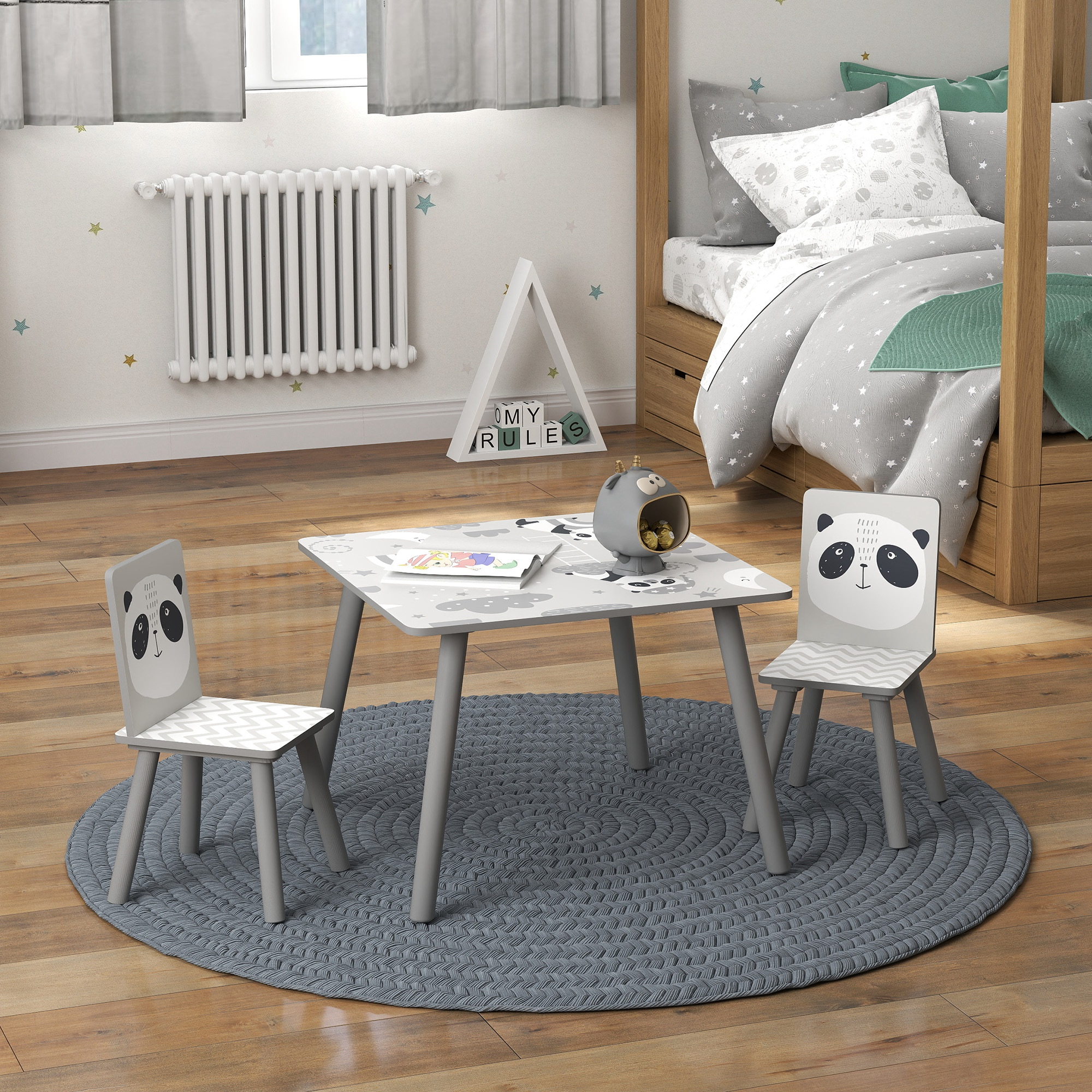 Una cameretta con tavolo e sedie a tema panda su un tappeto. Un letto è sullo sfondo, insieme a un radiatore e una finestra.