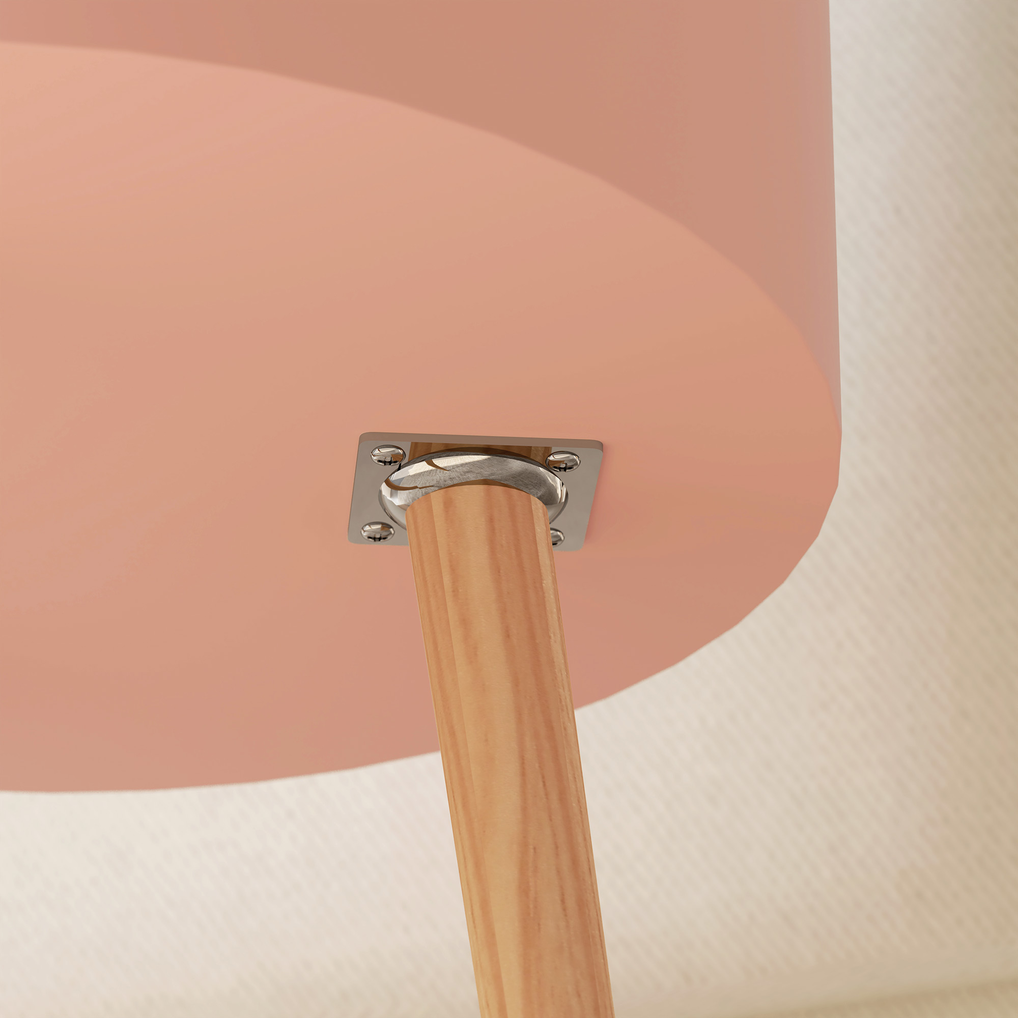 Primo piano del lato inferiore di un tavolo. Un piano del tavolo rosa ha una gamba in legno attaccata con una piastra di metallo, su sfondo strutturato.