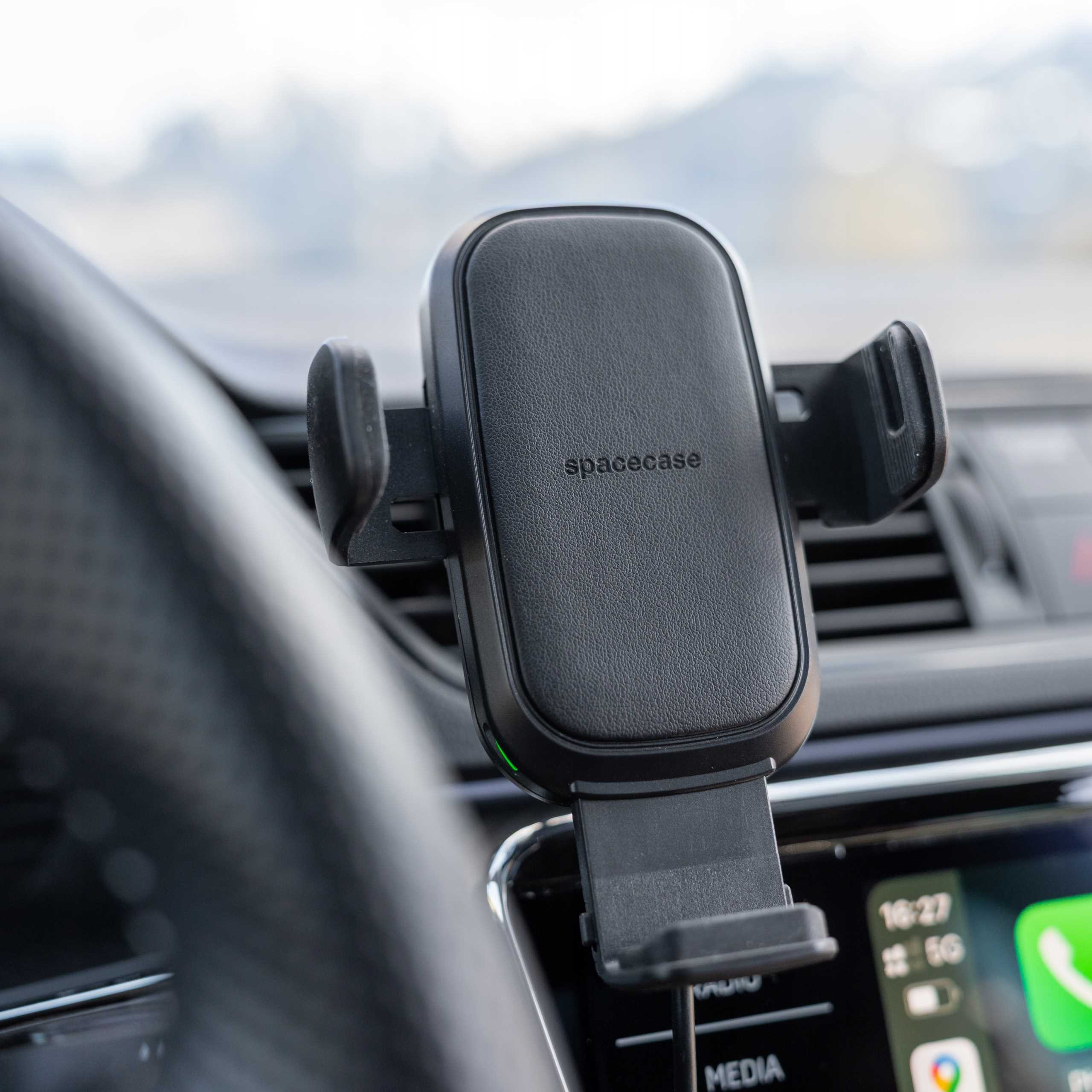 Czarny uchwyt na telefon w samochodzie. Uchwyt oznaczony 'spacecase'. Ekran wyświetla godzinę i aplikację nawigacyjną.